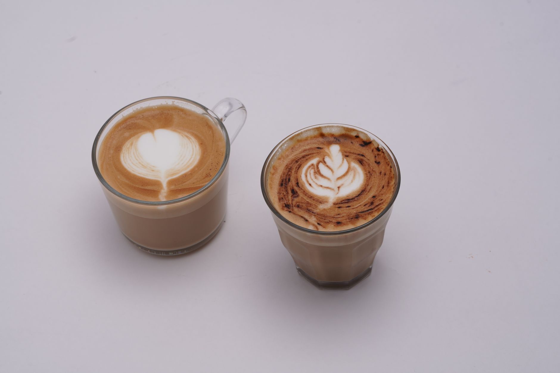 Two glass cups of specialty coffee with latte art side by side