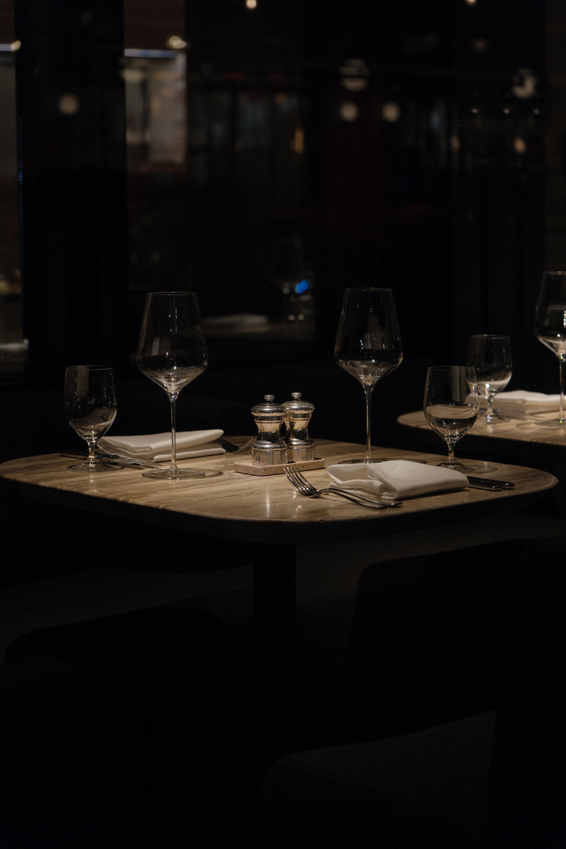 Table de restaurant élégante avec verres à vin et serviettes pliées dans une salle new-yorkaise tamisée