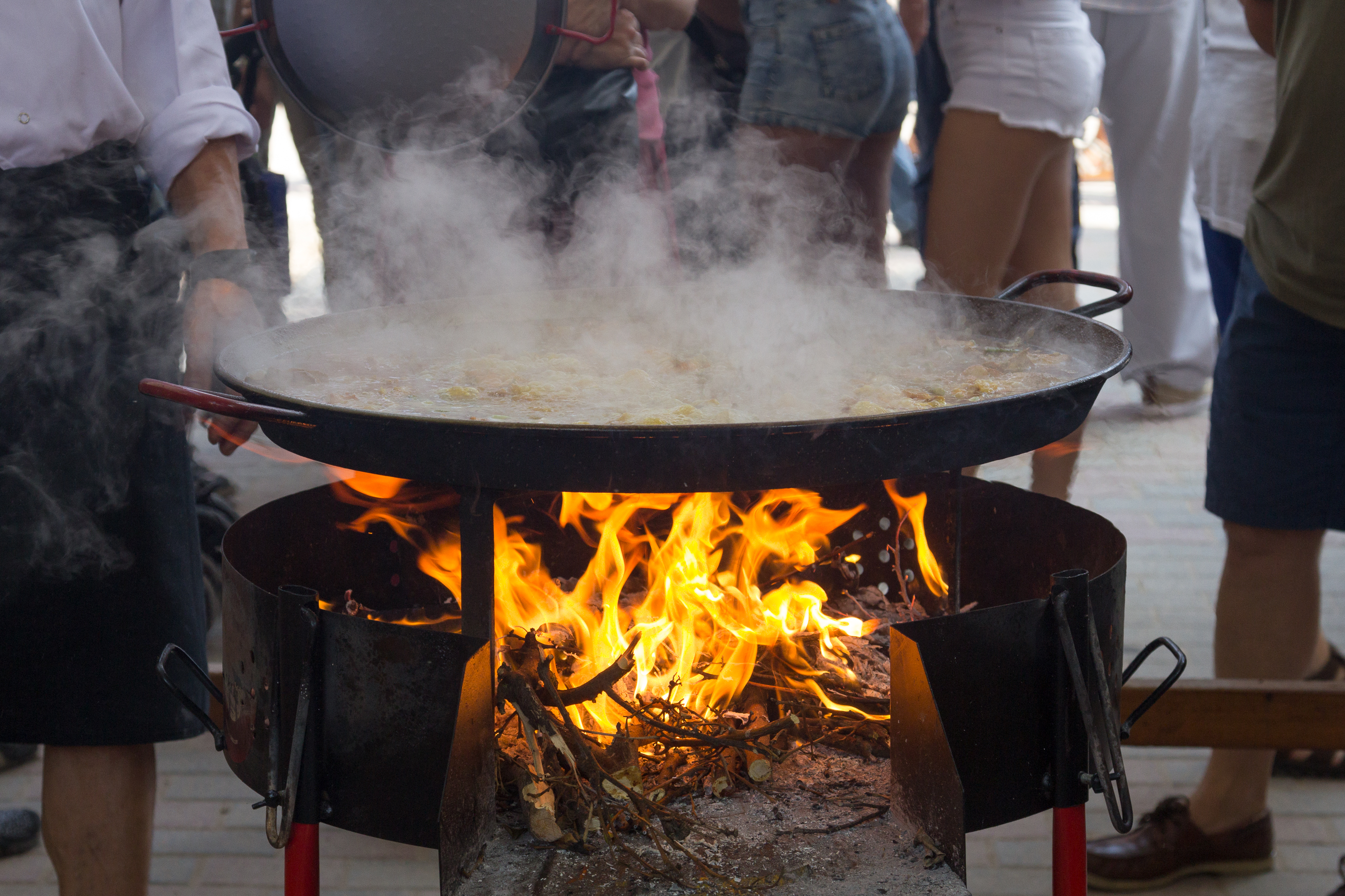 Grande padella da paella fumante sul fuoco a legna in un concorso a Sueca