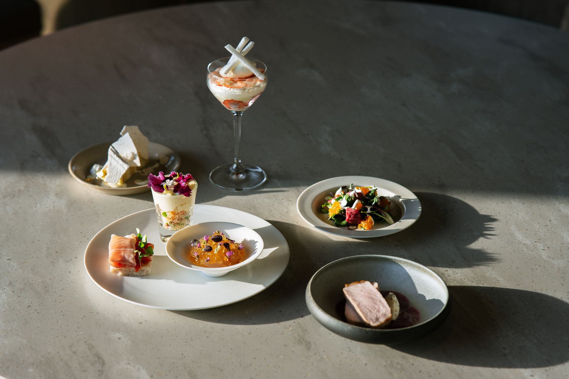 Small tasting-menu plates arranged on a stone table in natural light