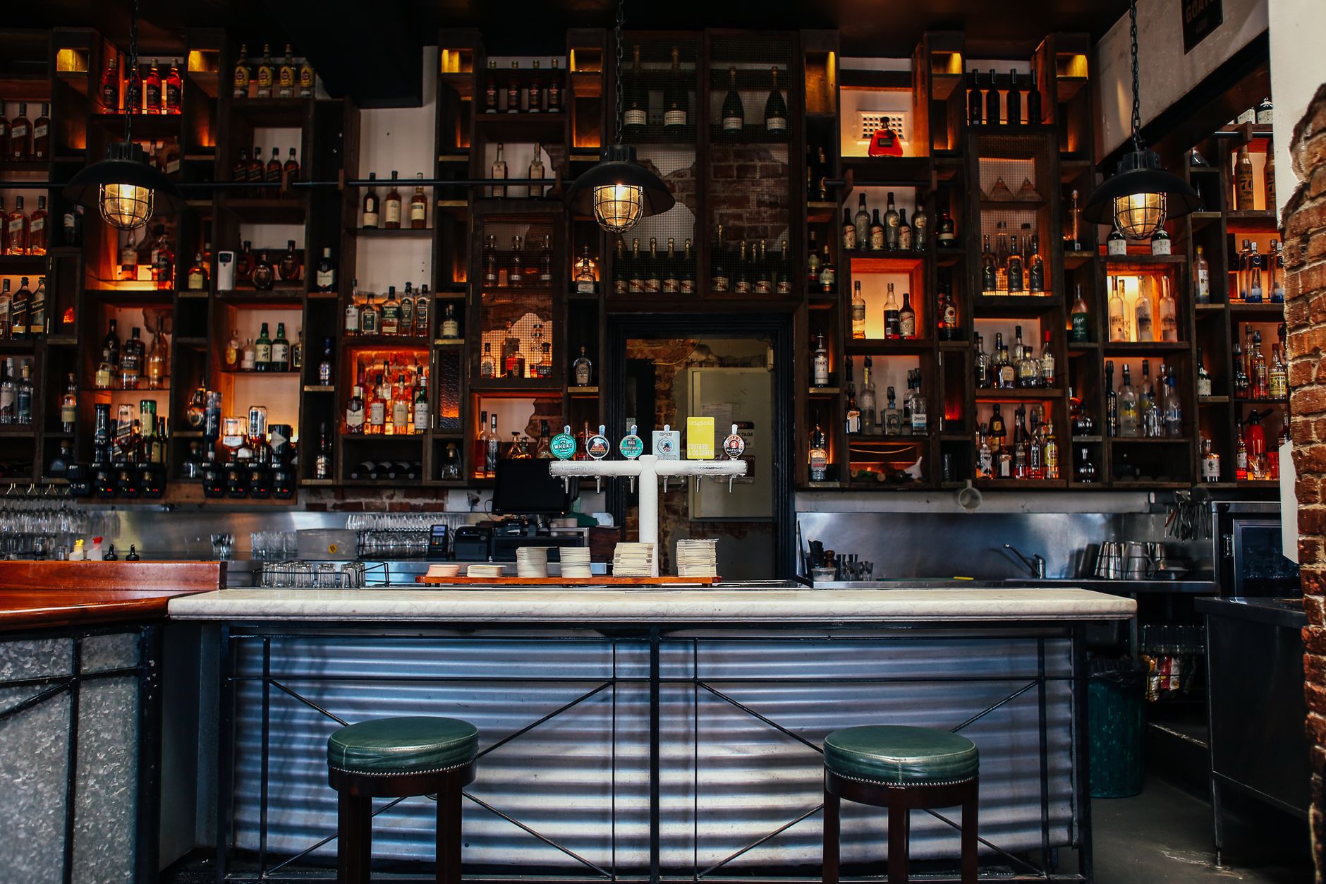 A backlit bottle wall and marble counter inside a modern London pub