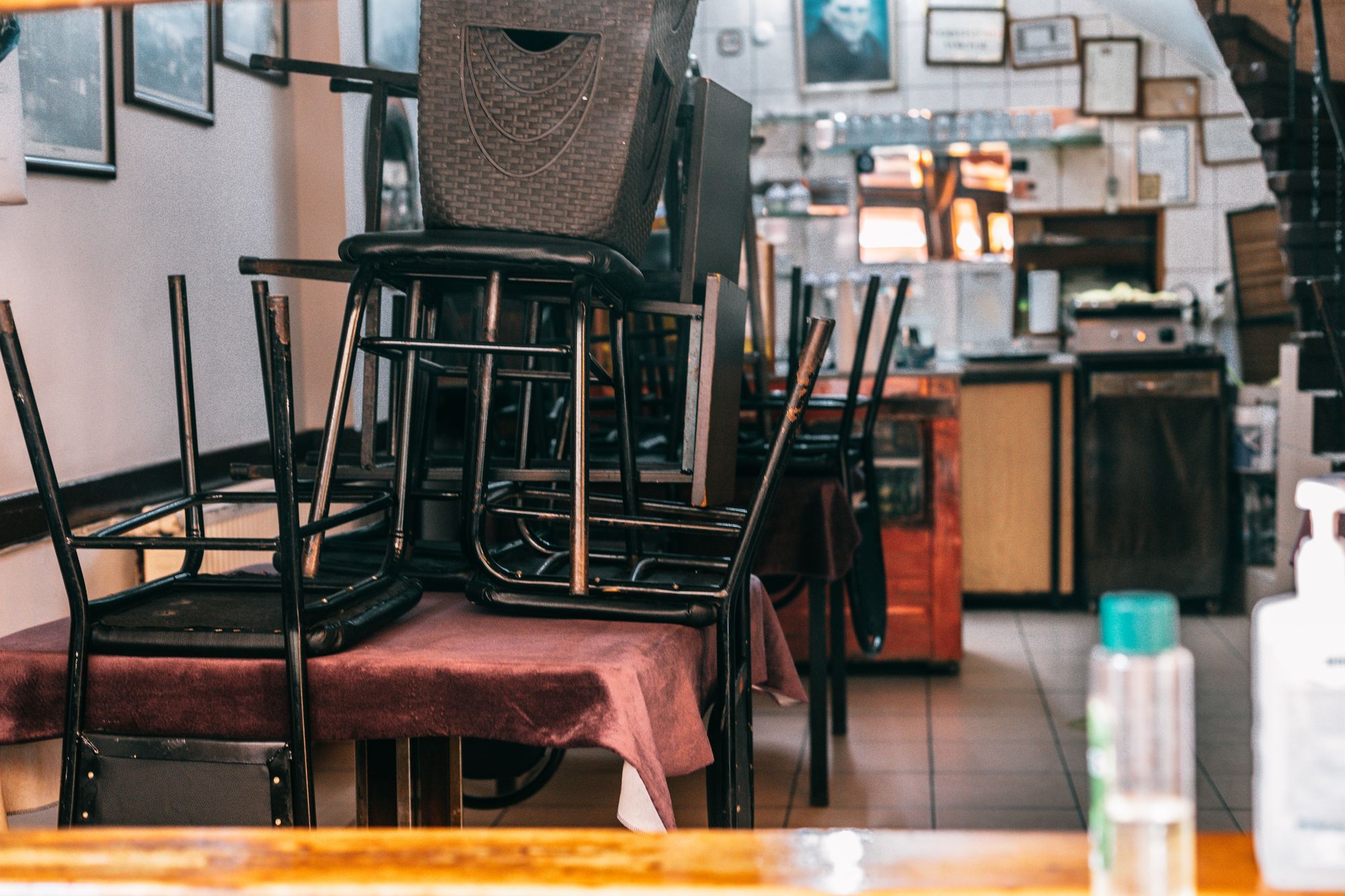 Chairs stacked on a cloth-covered table in a shuttered cafe dining room