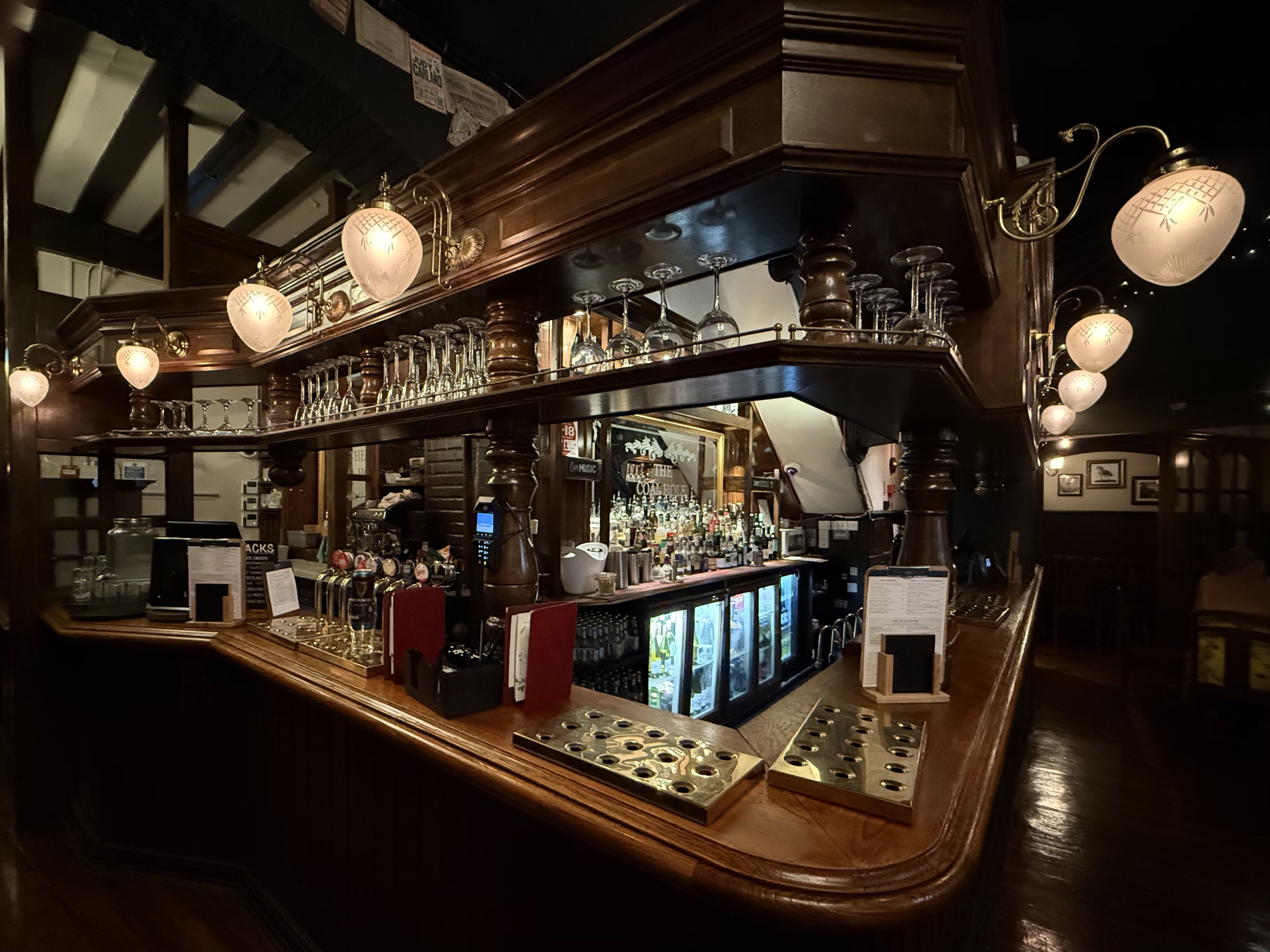 Comptoir en bois vide avec becs à bière en laiton et verrerie dans un pub traditionnel de Londres