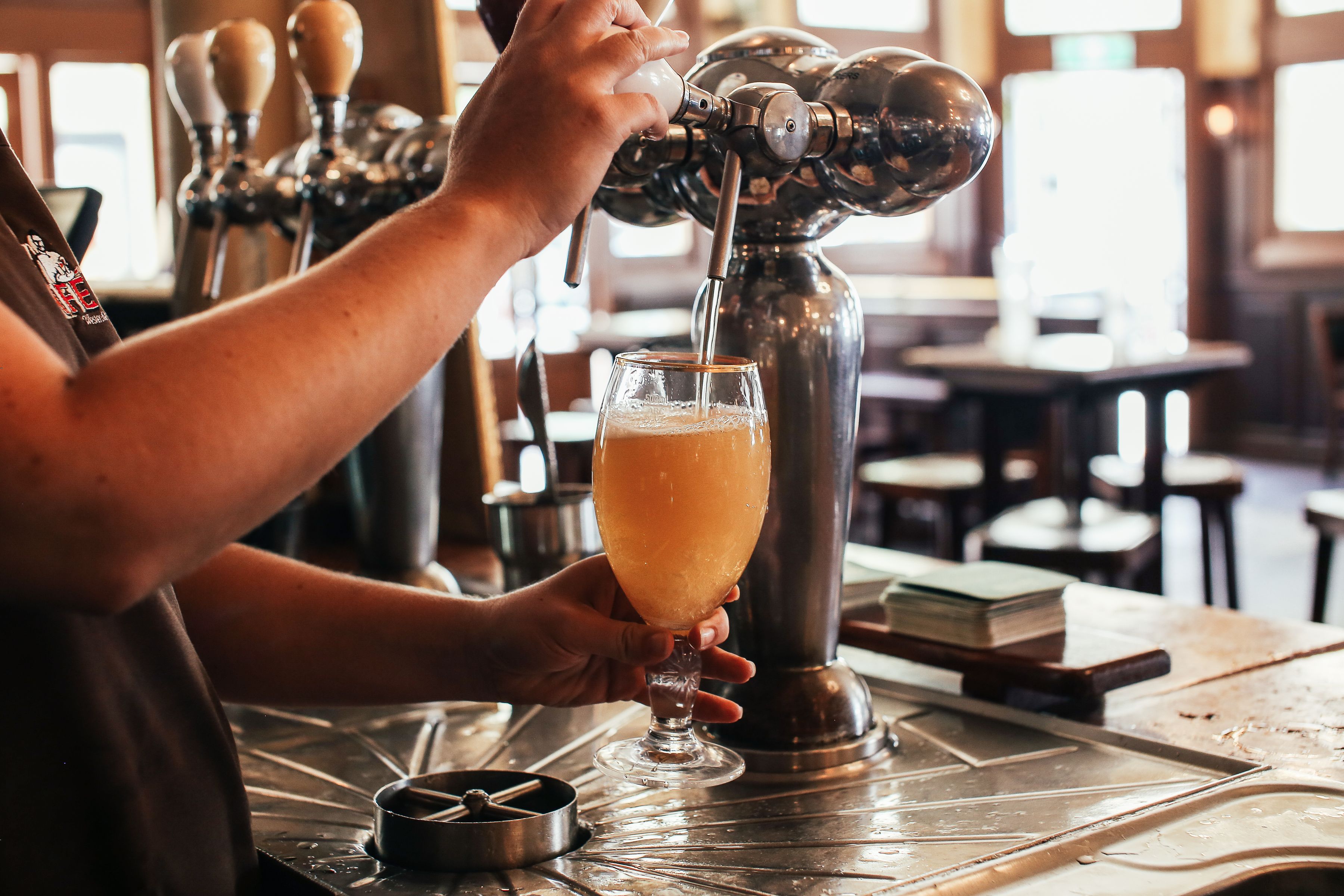 Bartender pouring a pint of beer from a tap in a pub