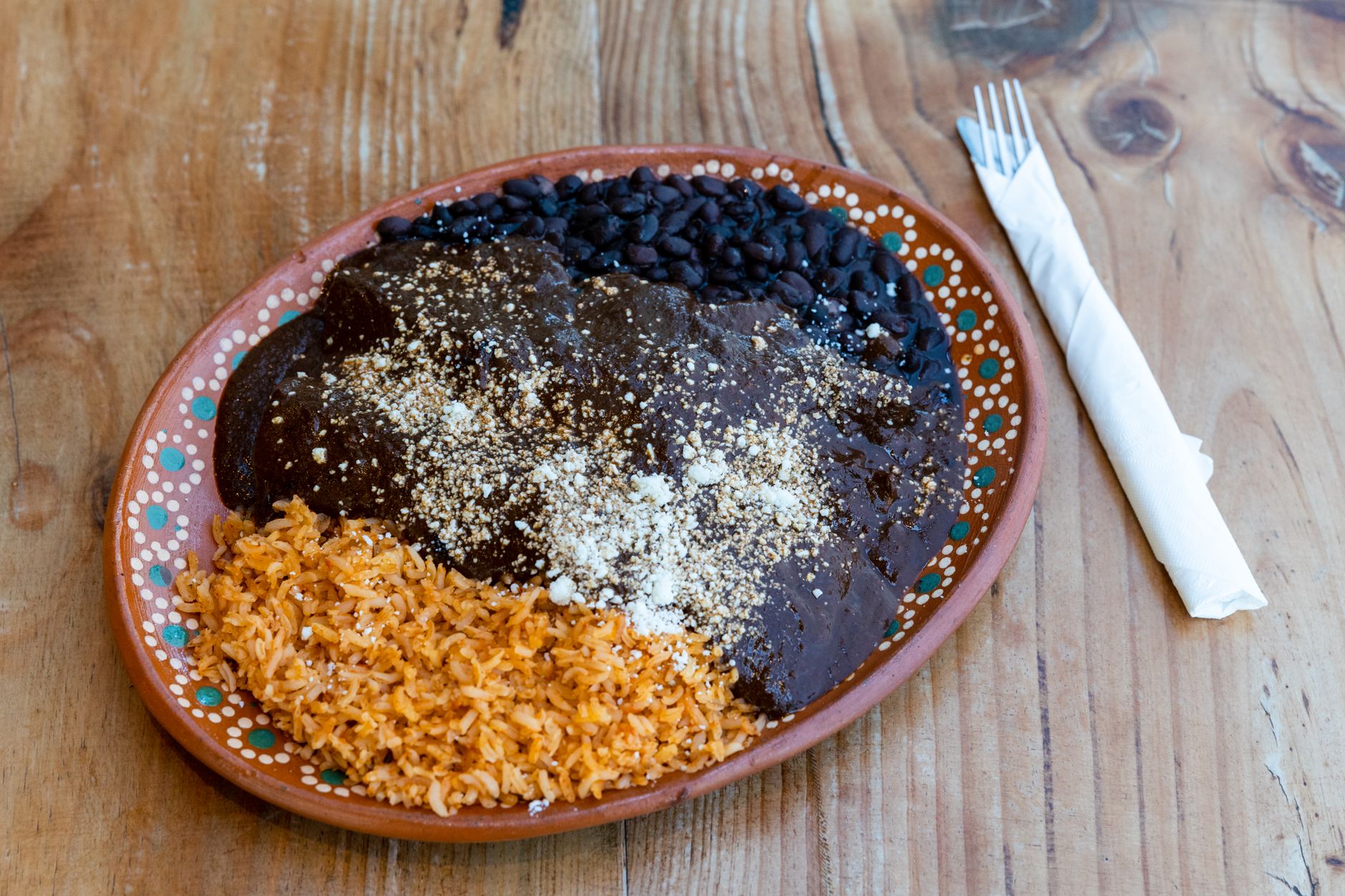 Plate of mole negro with black beans and rice on painted Oaxacan pottery