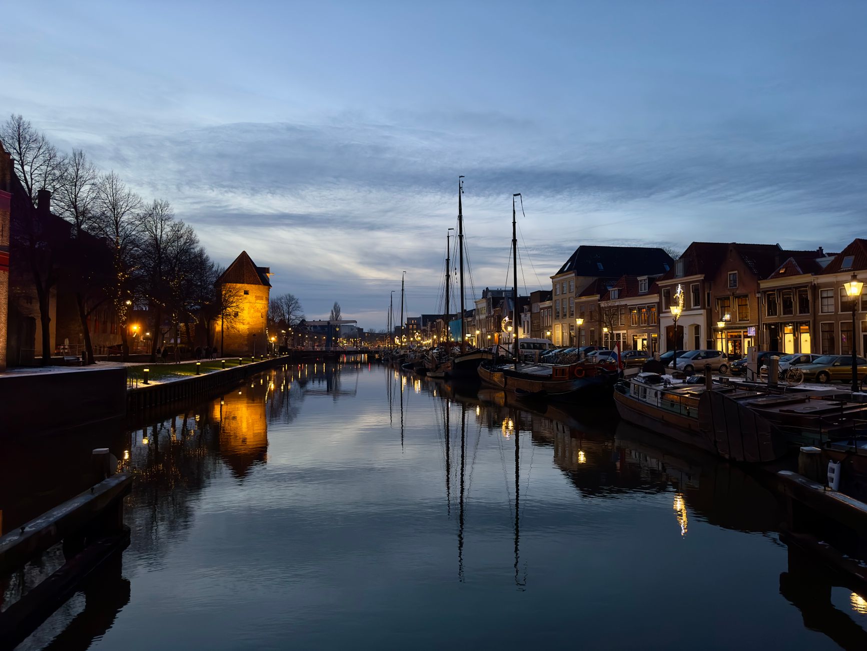 Historic canal in Zwolle at dusk lined with boats and gabled houses