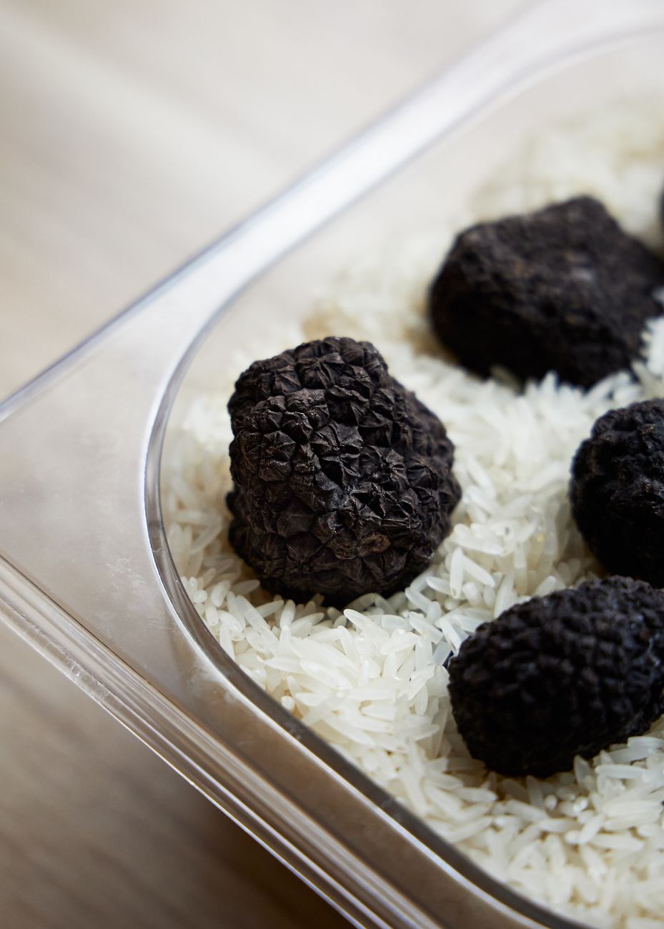 Hele zwarte en witte truffels op een bedje van rauwe carnaroli-rijst