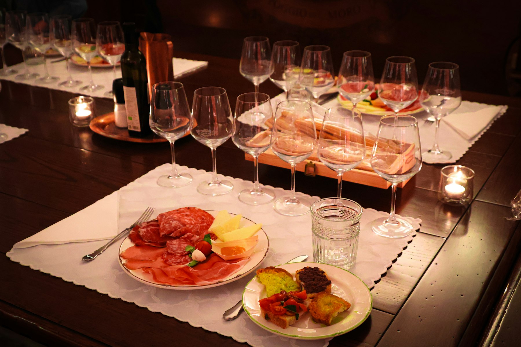 Charcuterie, bread and wine glasses laid out on a candlelit wine bar table