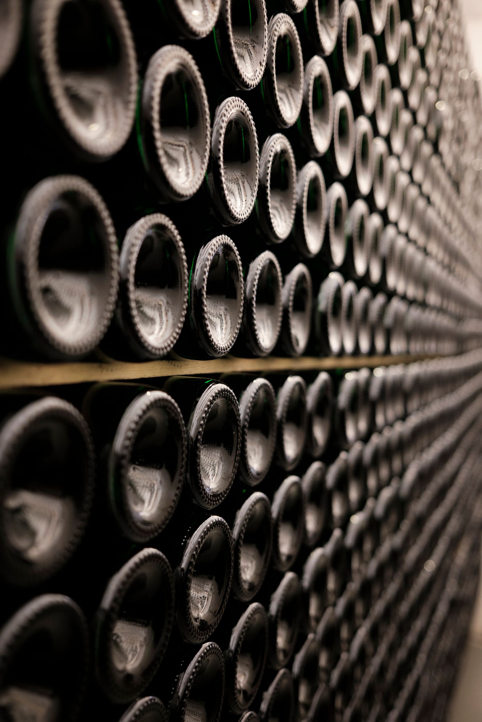 Close-up of wine bottles ageing in rows in a dark cellar