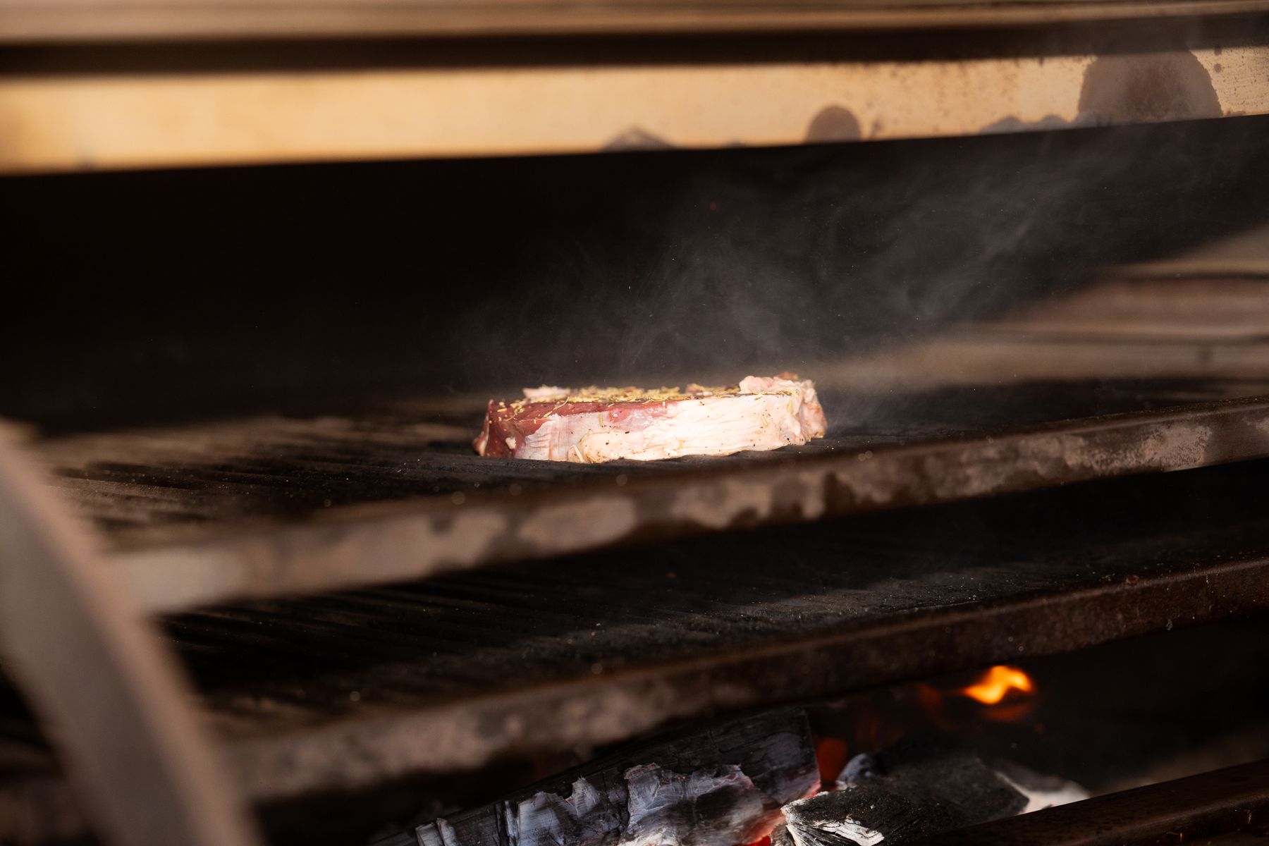 Un filete sazonado se dora sobre las brasas de una parrilla de restaurante
