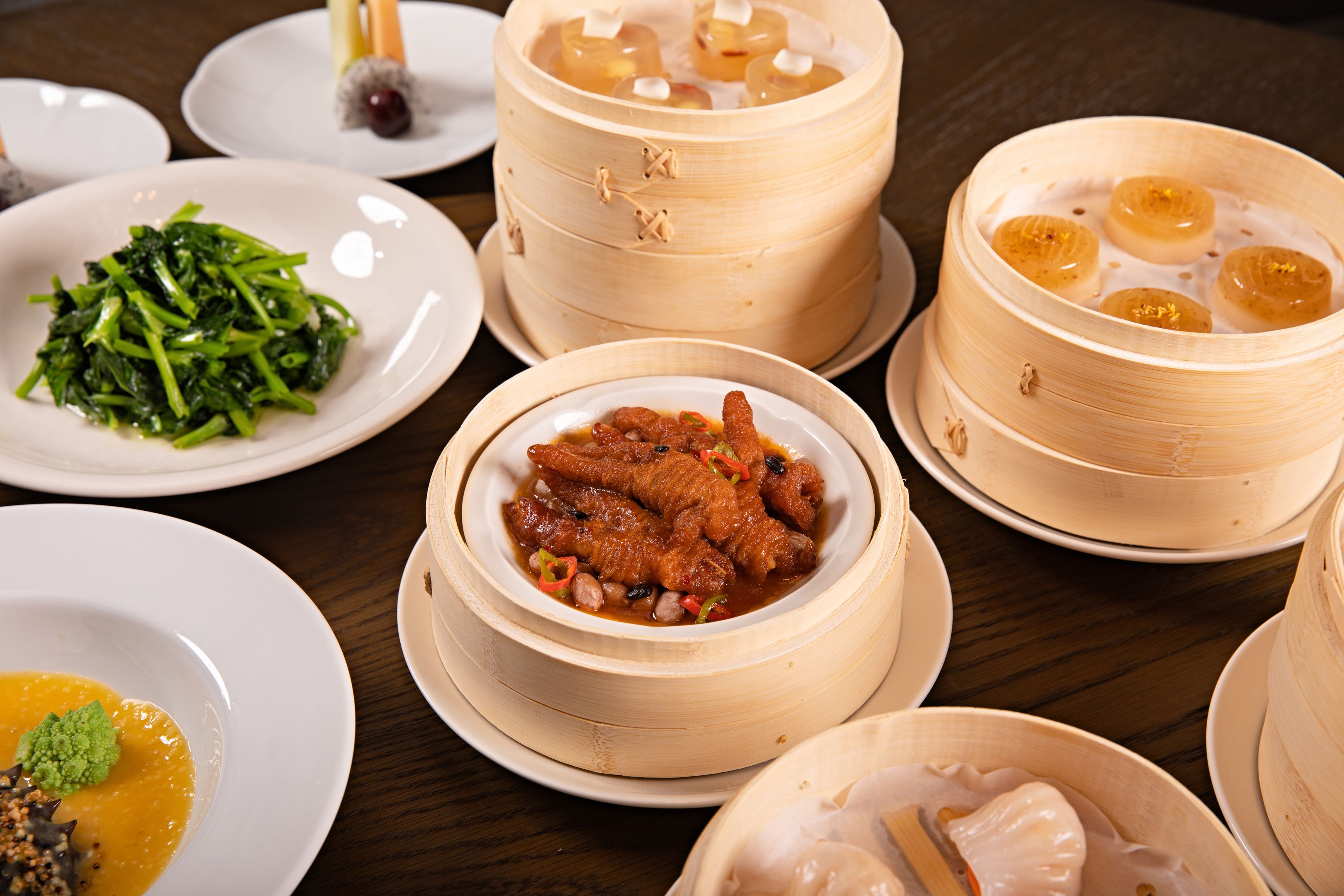 Paniers en bambou de dim sum, raviolis et légumes sur une table sombre