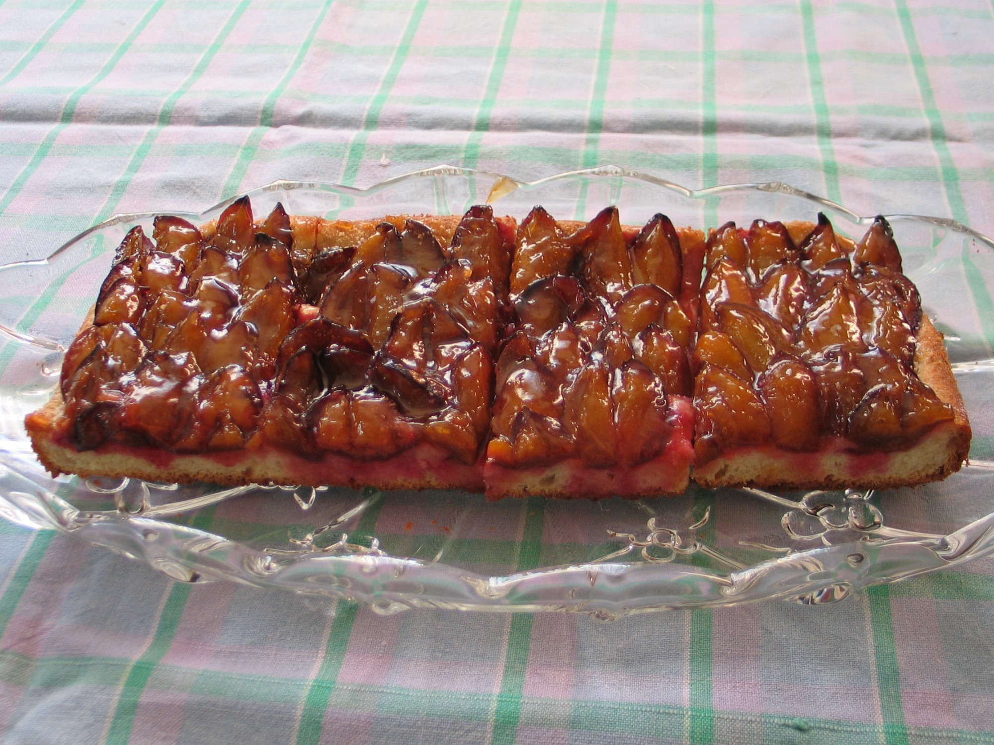 Slices of Zwetschgendatschi with glazed plum halves packed in rows on yeast dough