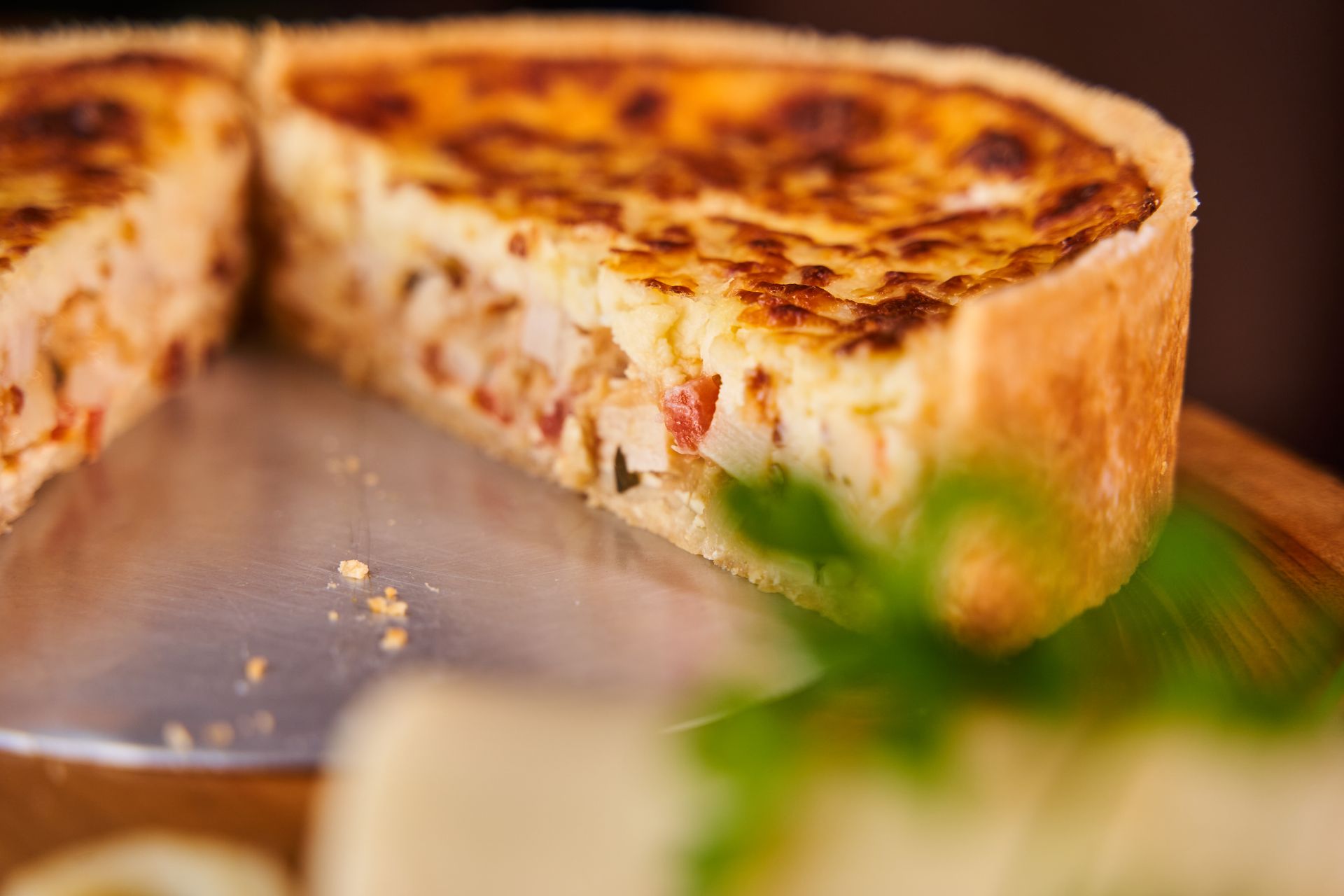 Savoury tart with a golden crust cut open to show its set custard filling