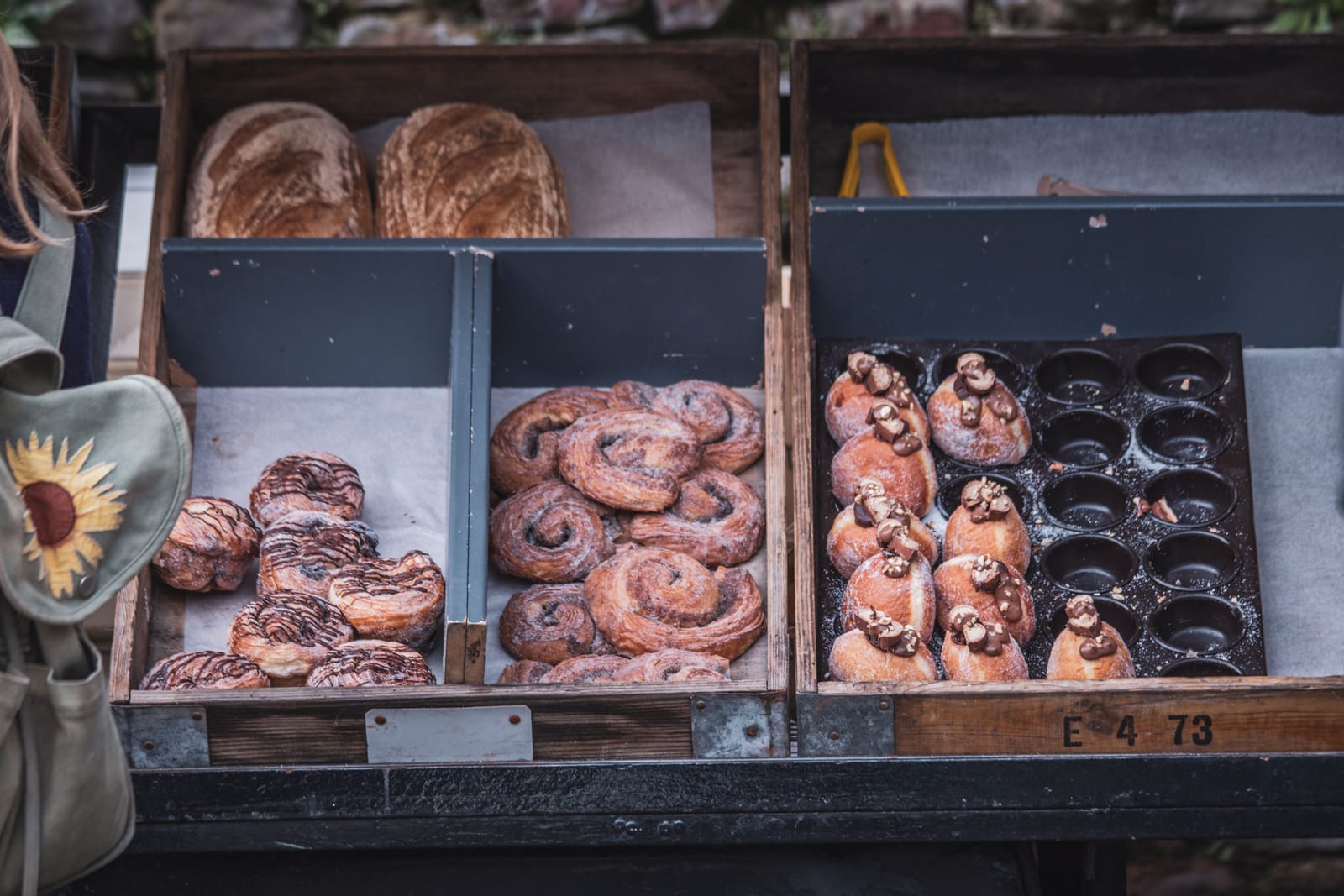 Sourdough loaves and pastries displayed in wooden crates at a market bakery stall