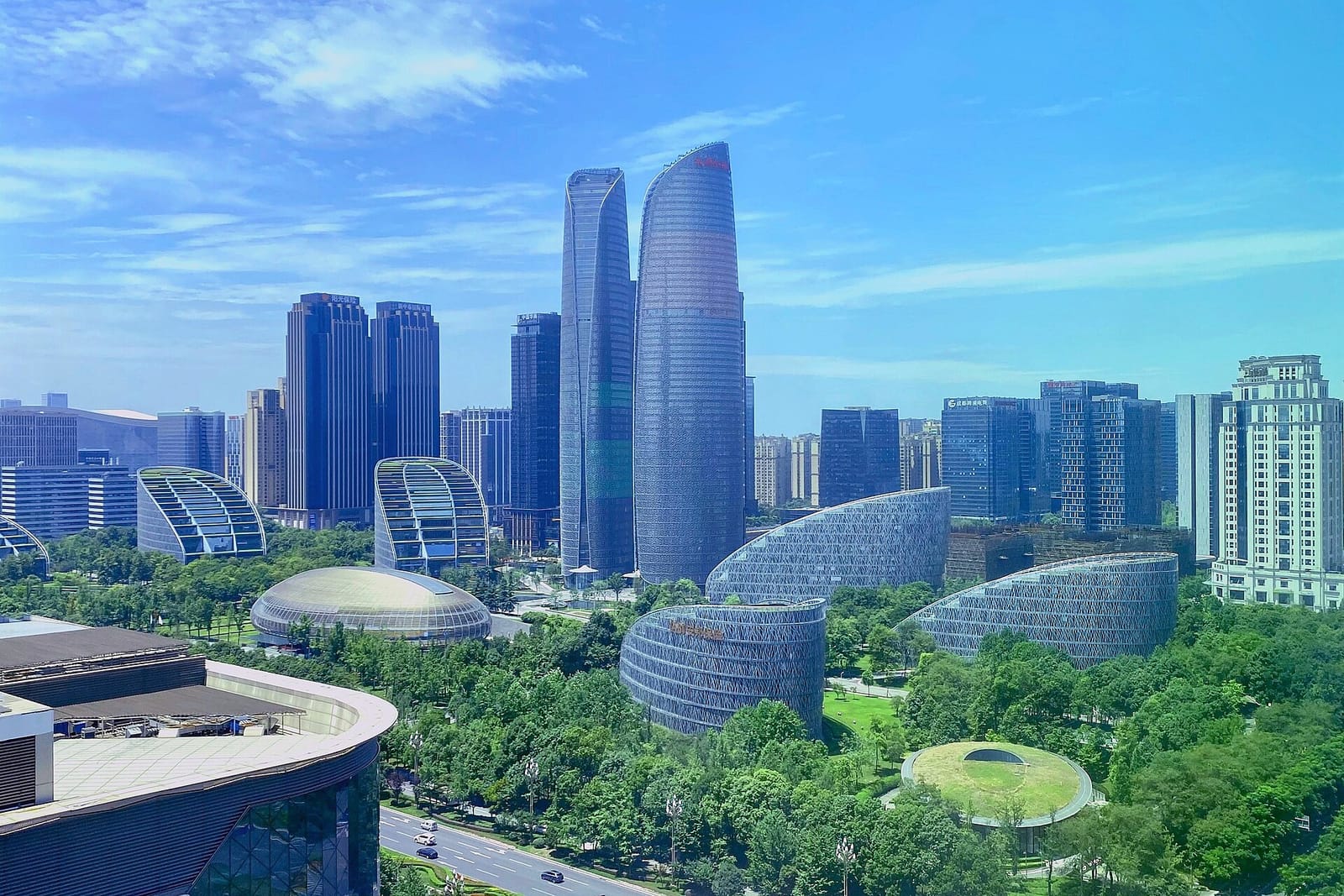 Tours de verre et pavillons arrondis du quartier financier de Chengdu entre les arbres sous un ciel bleu