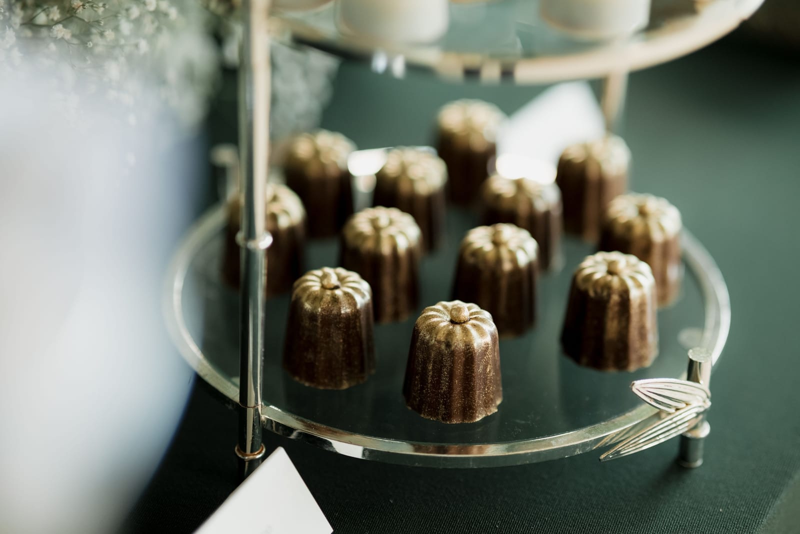 Dunkle, karamellisierte Canelés aus Bordeaux auf einer Glasplatte