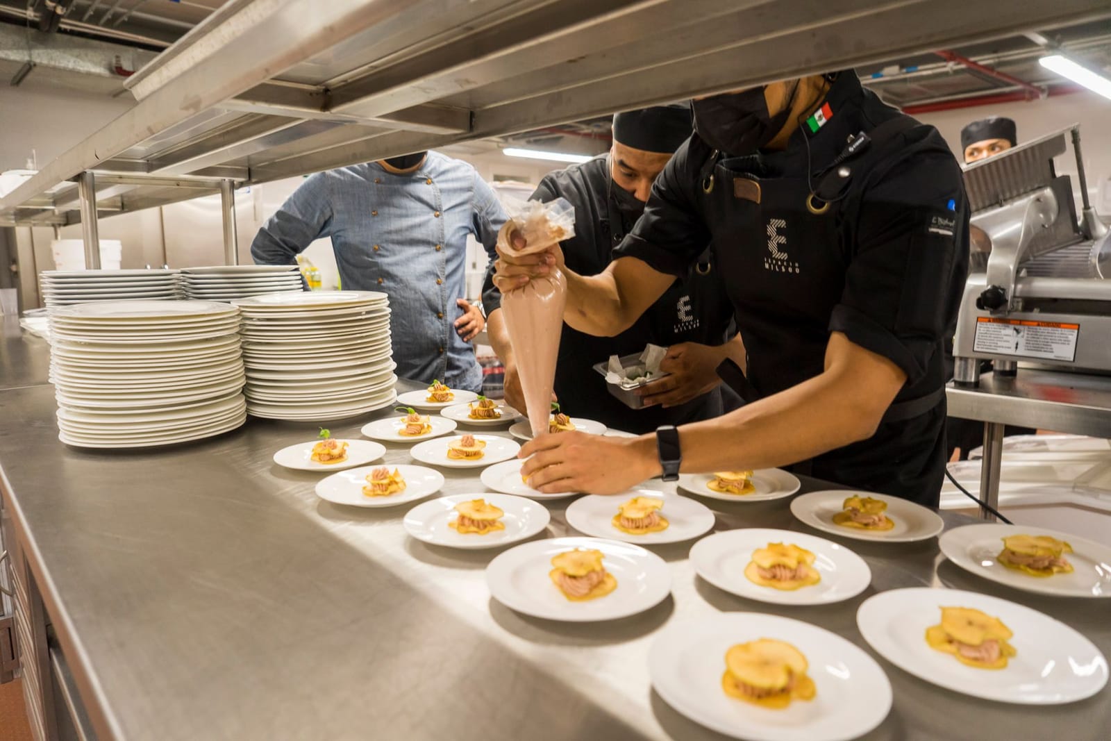 Hotel chef in white uniform plating a dish in a modern resort kitchen