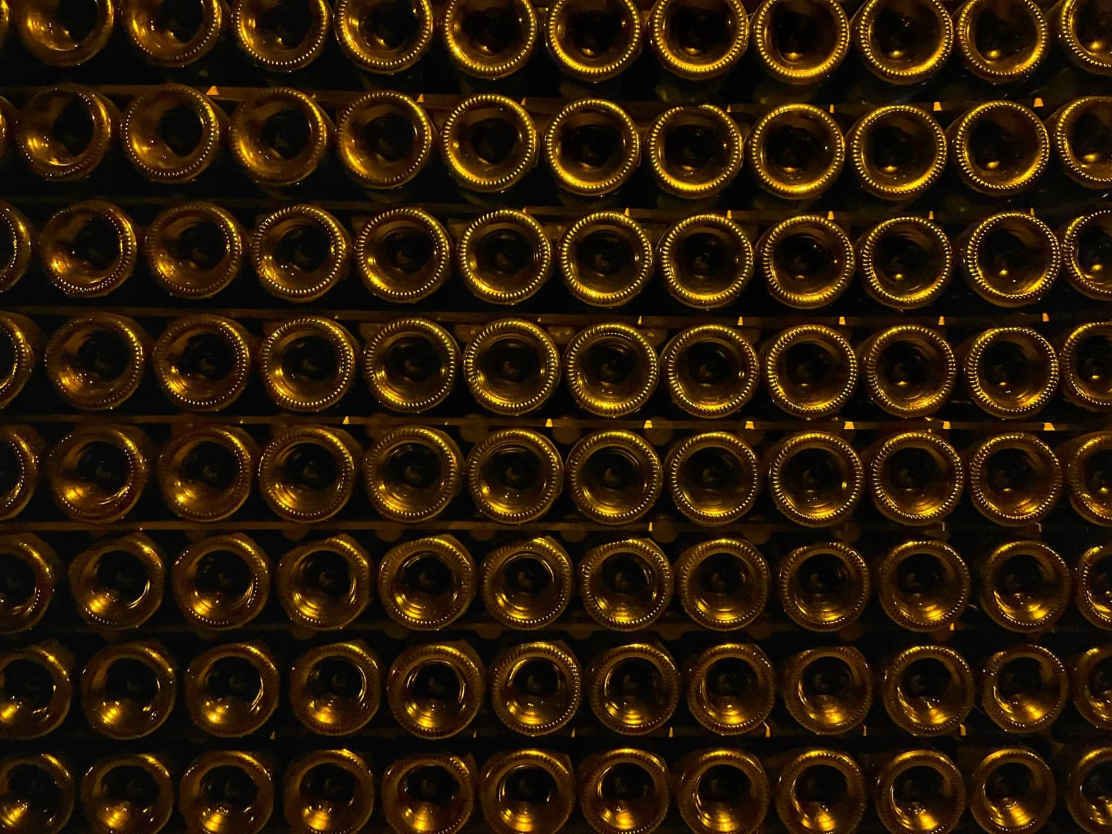 Rows of wine bottles aging in a dimly lit cellar rack