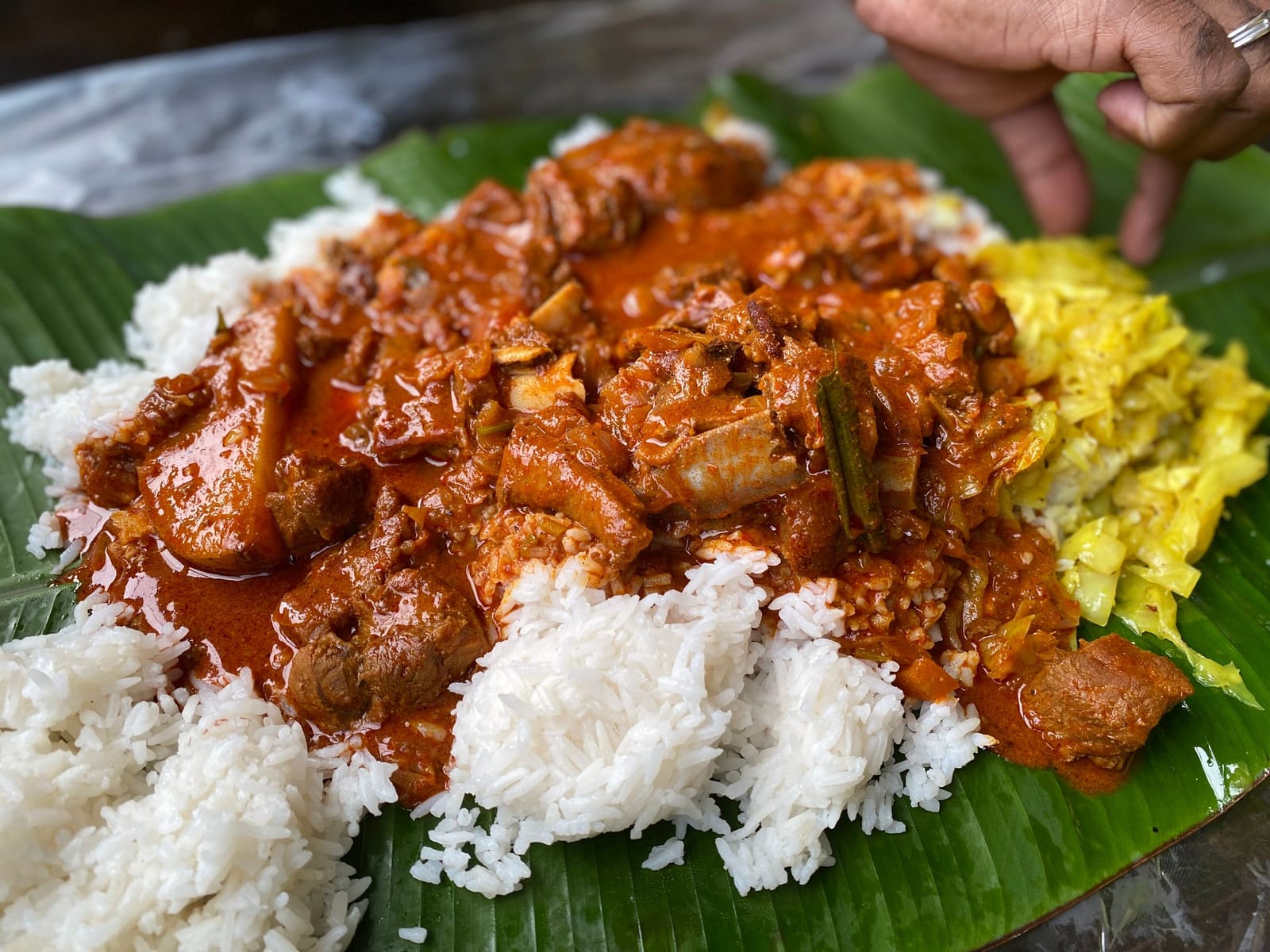Rice with a red meat curry and cabbage served on a banana leaf