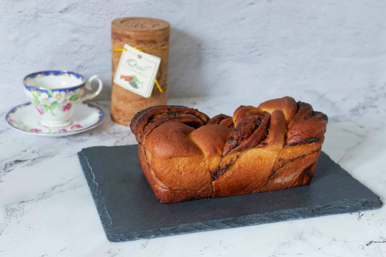 Ein geflochtener Schokoladen-Babka auf einem dunklen Schieferbrett