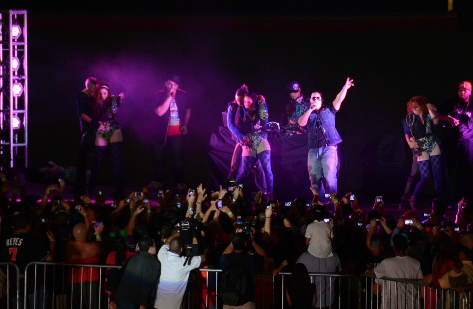 Daddy Yankee performing on a lit stage in front of a crowd holding up phones