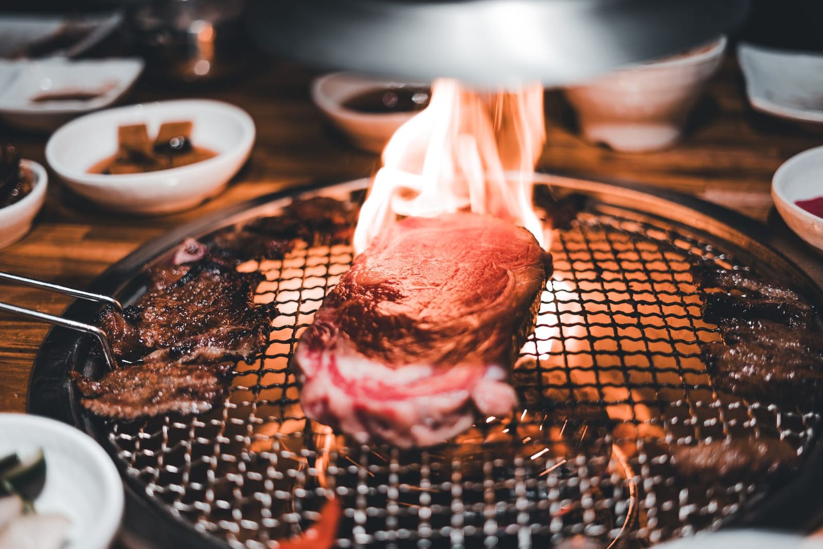 Marbled beef grills over an open flame on a Korean barbecue tabletop grill