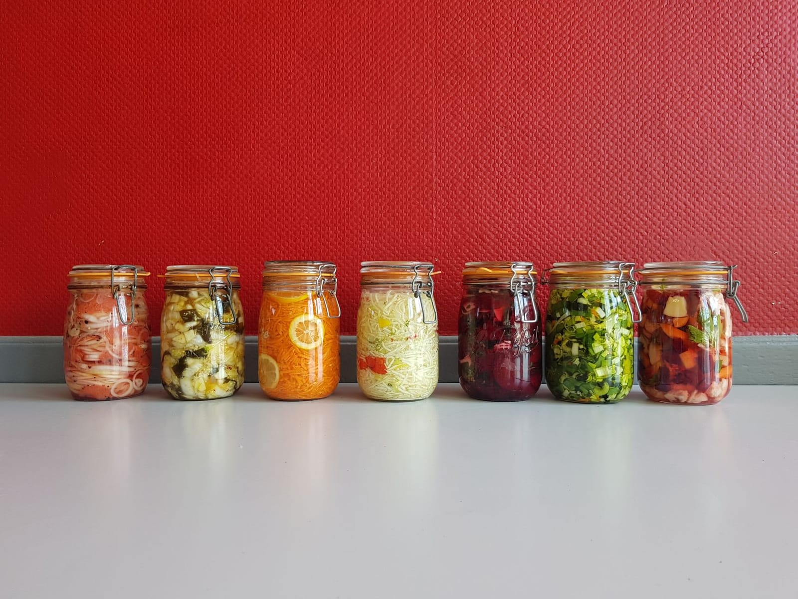 Rows of glass jars filled with colourful fermented vegetables and pickles