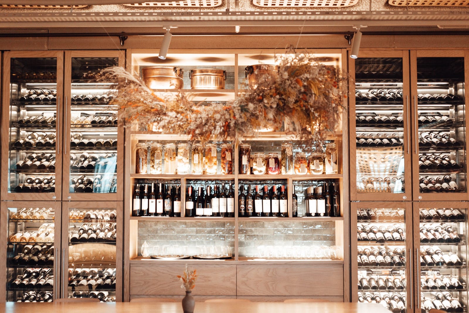 Glass-fronted wine cabinets and shelved bottles lit warmly inside a fine-dining restaurant