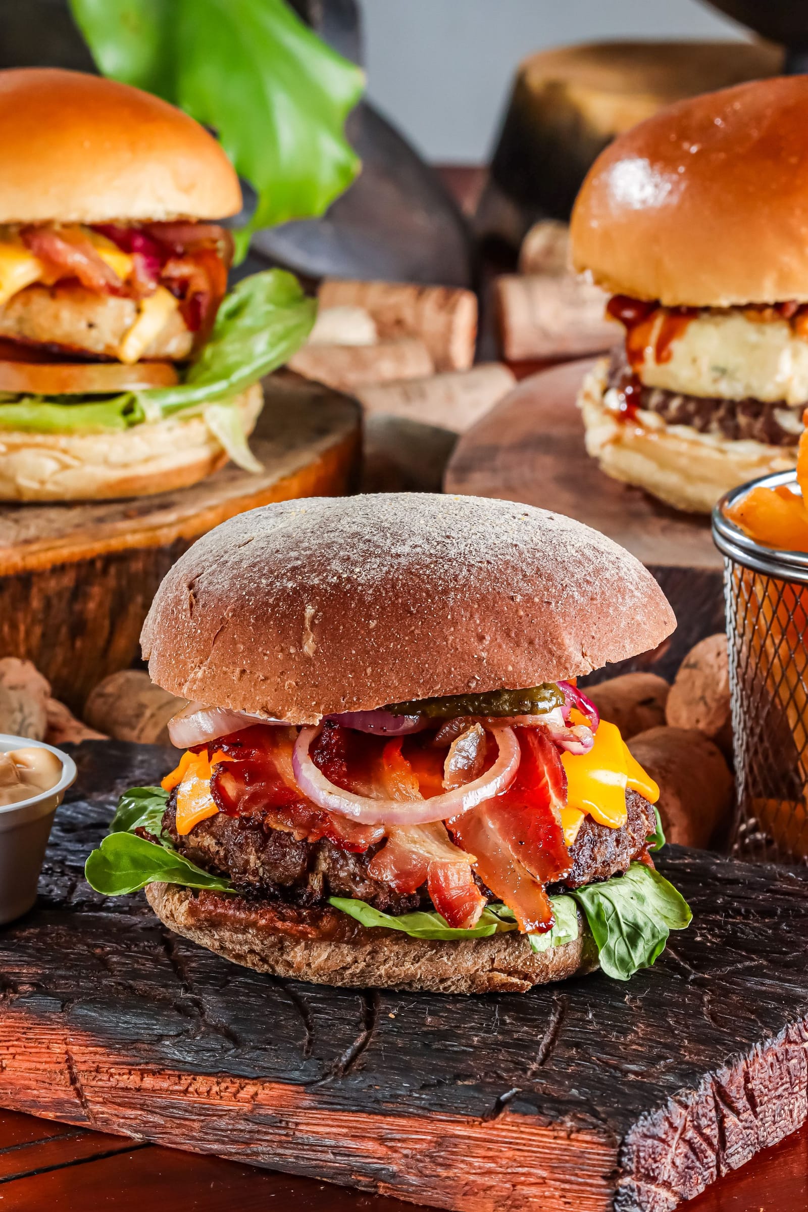 Gourmet burgers with cheese and bacon served on wooden boards