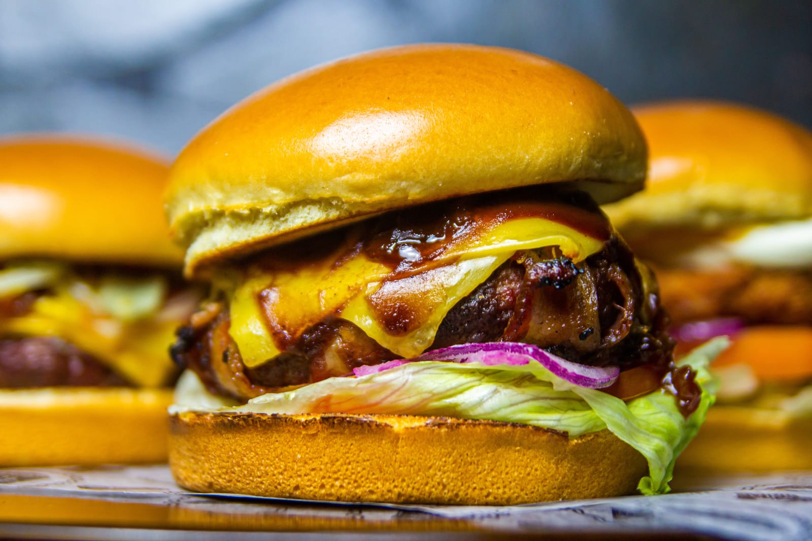 Primer plano de una hamburguesa gourmet apilada con queso fundido y beicon