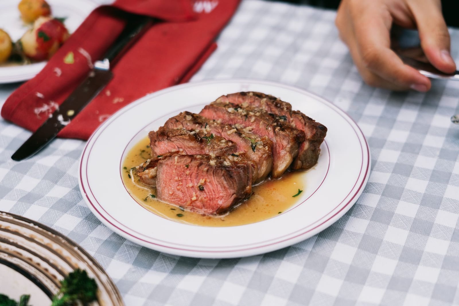 Sliced grilled steak with pan juices served on a white plate