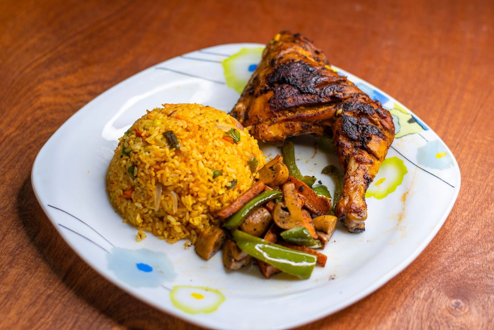 Smoky jollof rice served with grilled chicken and vegetables on a plate