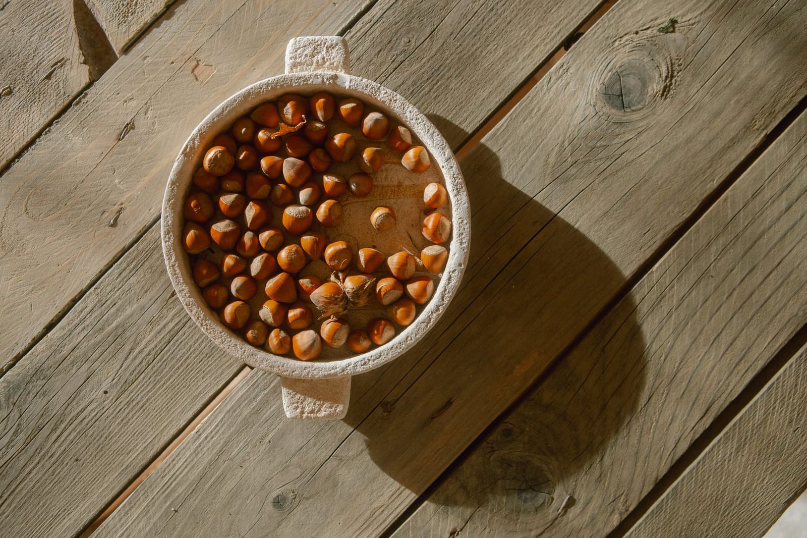 Whole and shelled hazelnuts in a rustic bowl, the nuts behind Linzer torte's pastry