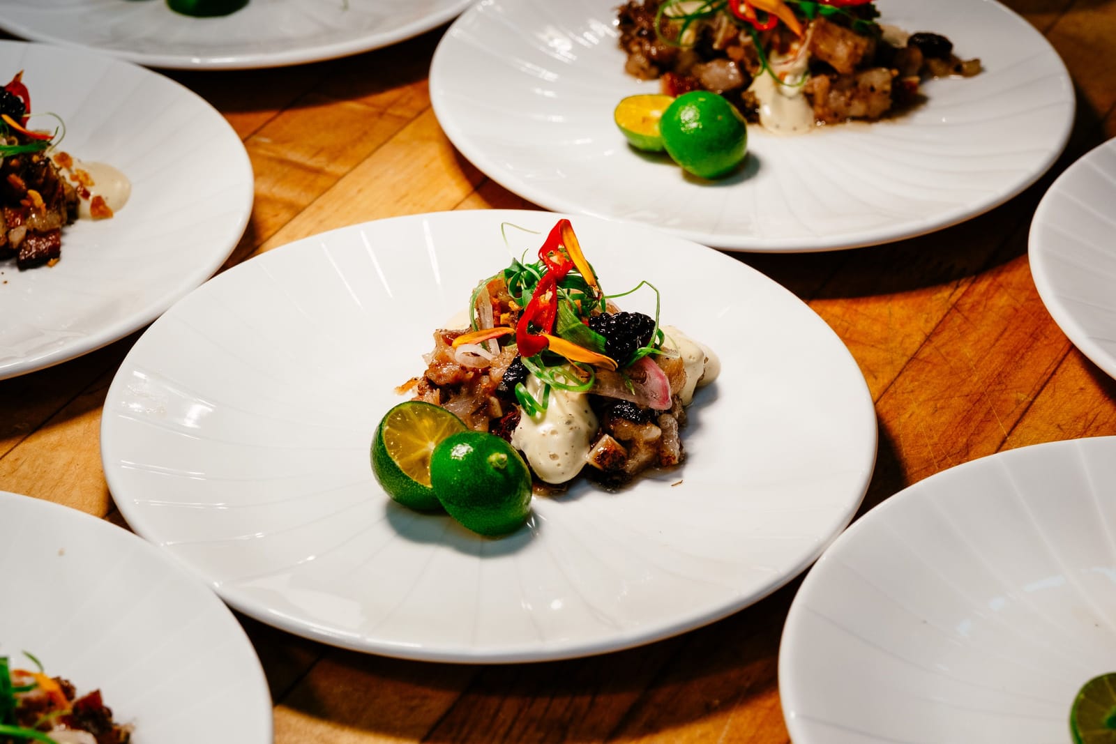 Elegant angerichtetes philippinisches Gericht mit Zitrusfrüchten, Chili und Kräutern auf weißem Teller