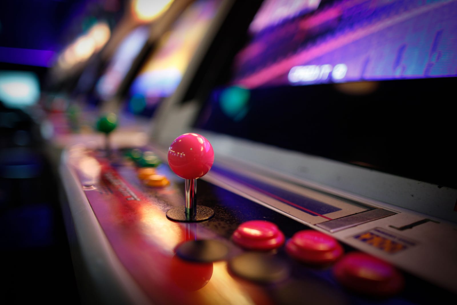 A pink joystick and arcade buttons lit in neon pink and blue