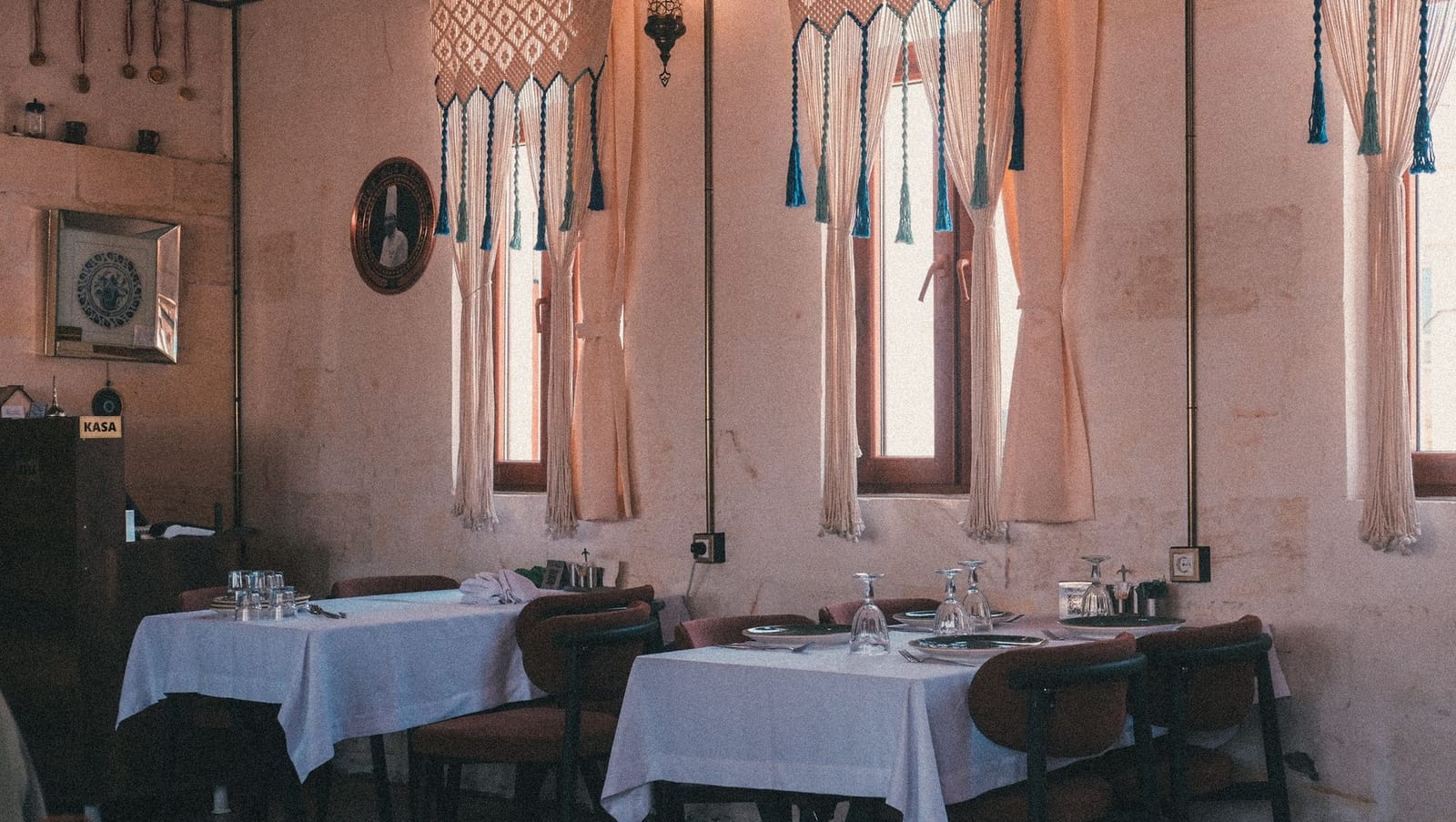 Elegant Mediterranean restaurant dining room with soft pink walls and patterned drapes