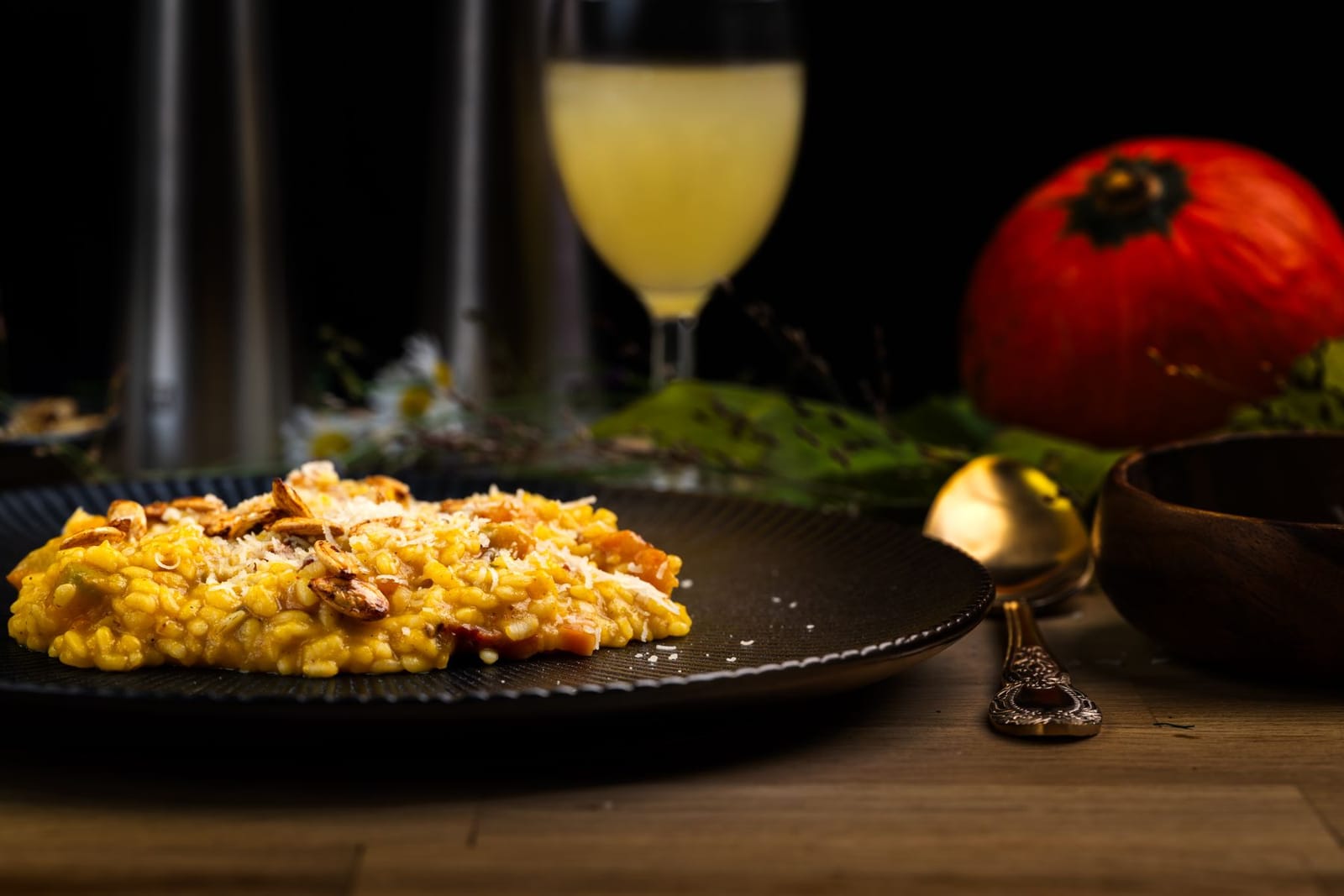 Risotto cremoso de calabaza con pipas tostadas y parmesano en un plato oscuro