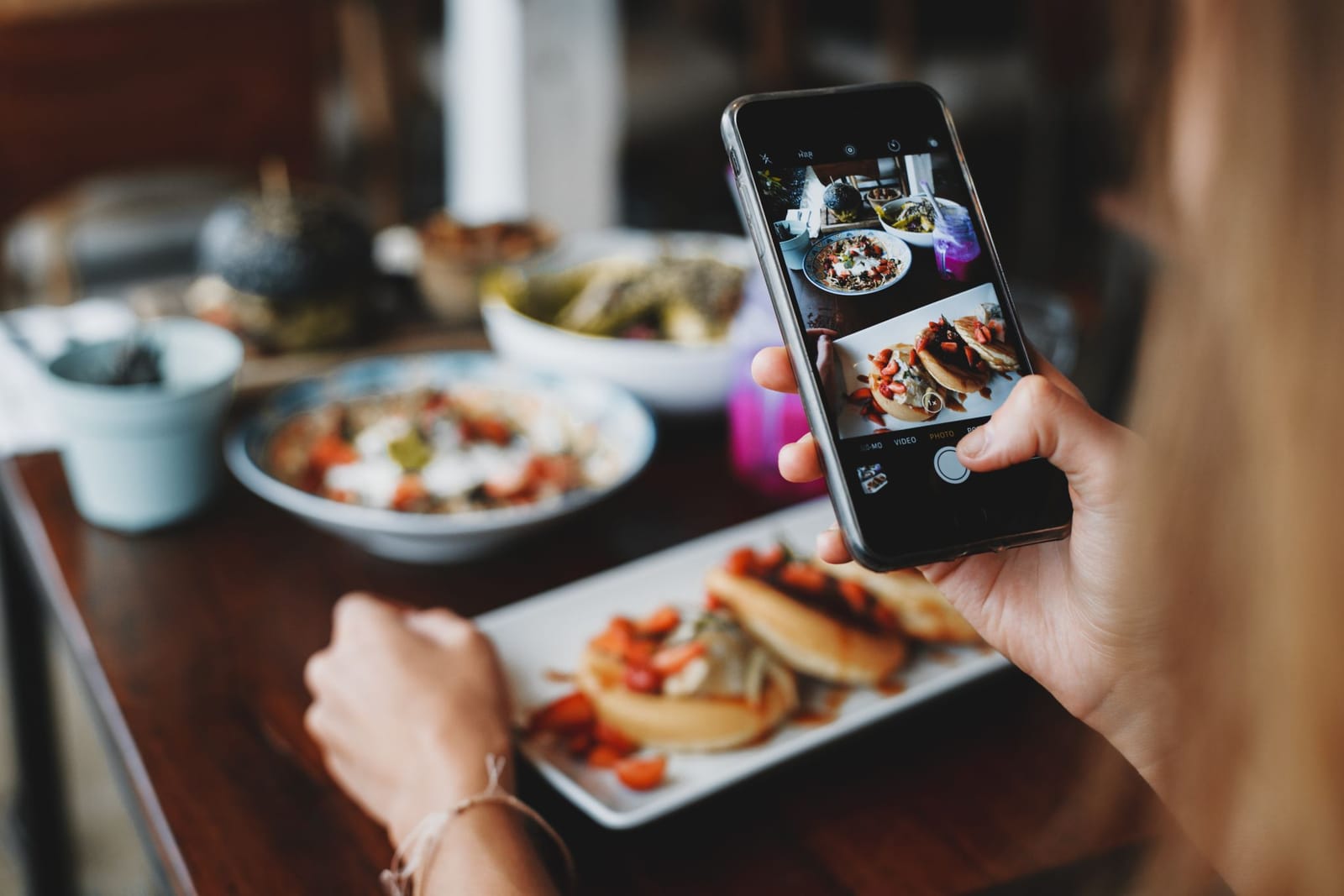 Diner photographing a restaurant meal on a smartphone