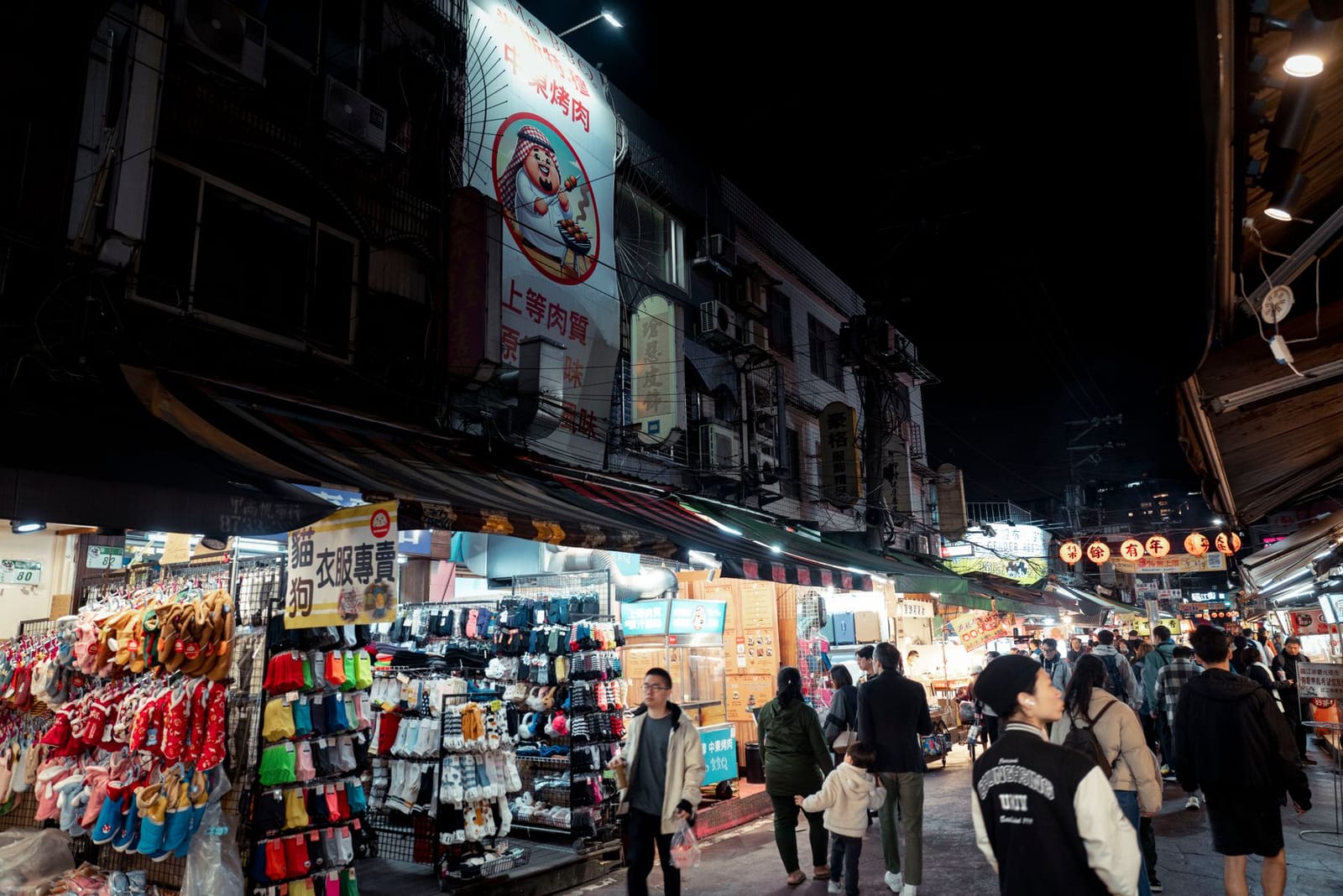 Gente caminando entre puestos de comida iluminados en un mercado nocturno de Taipéi