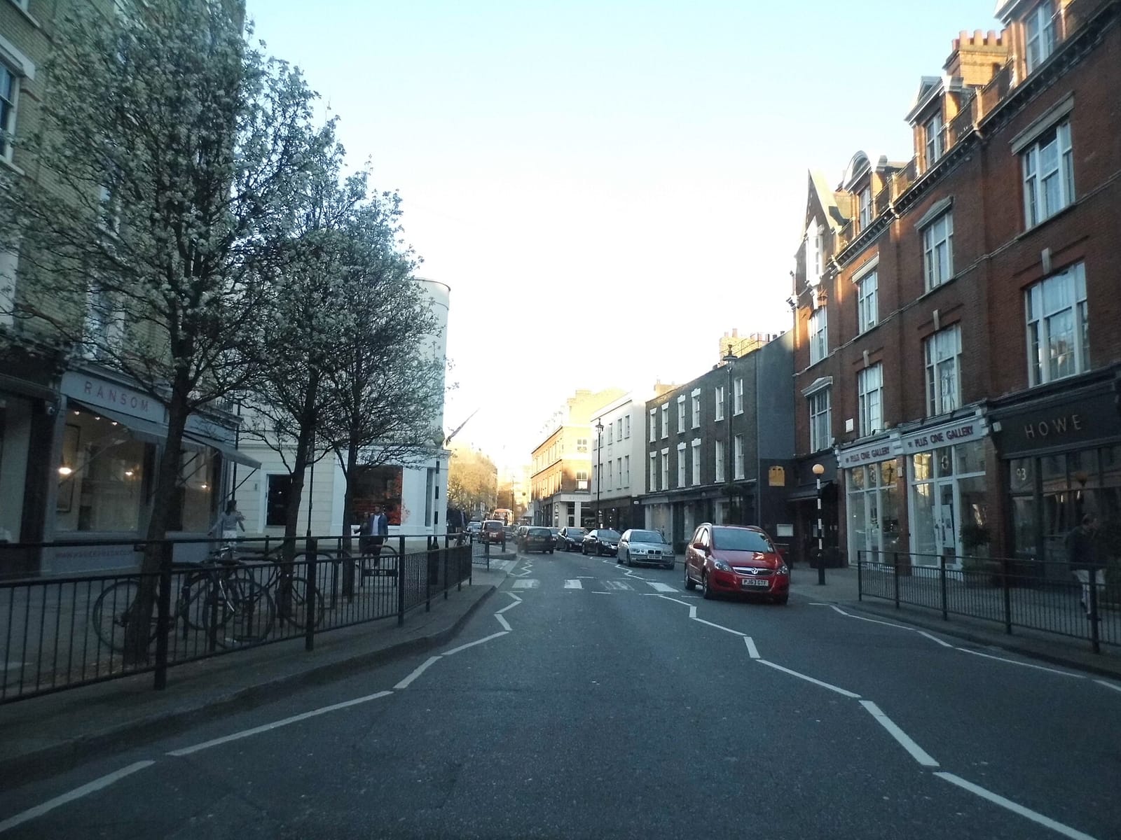 Pimlico Road in Belgravia with shopfronts, parked cars and blossoming trees
