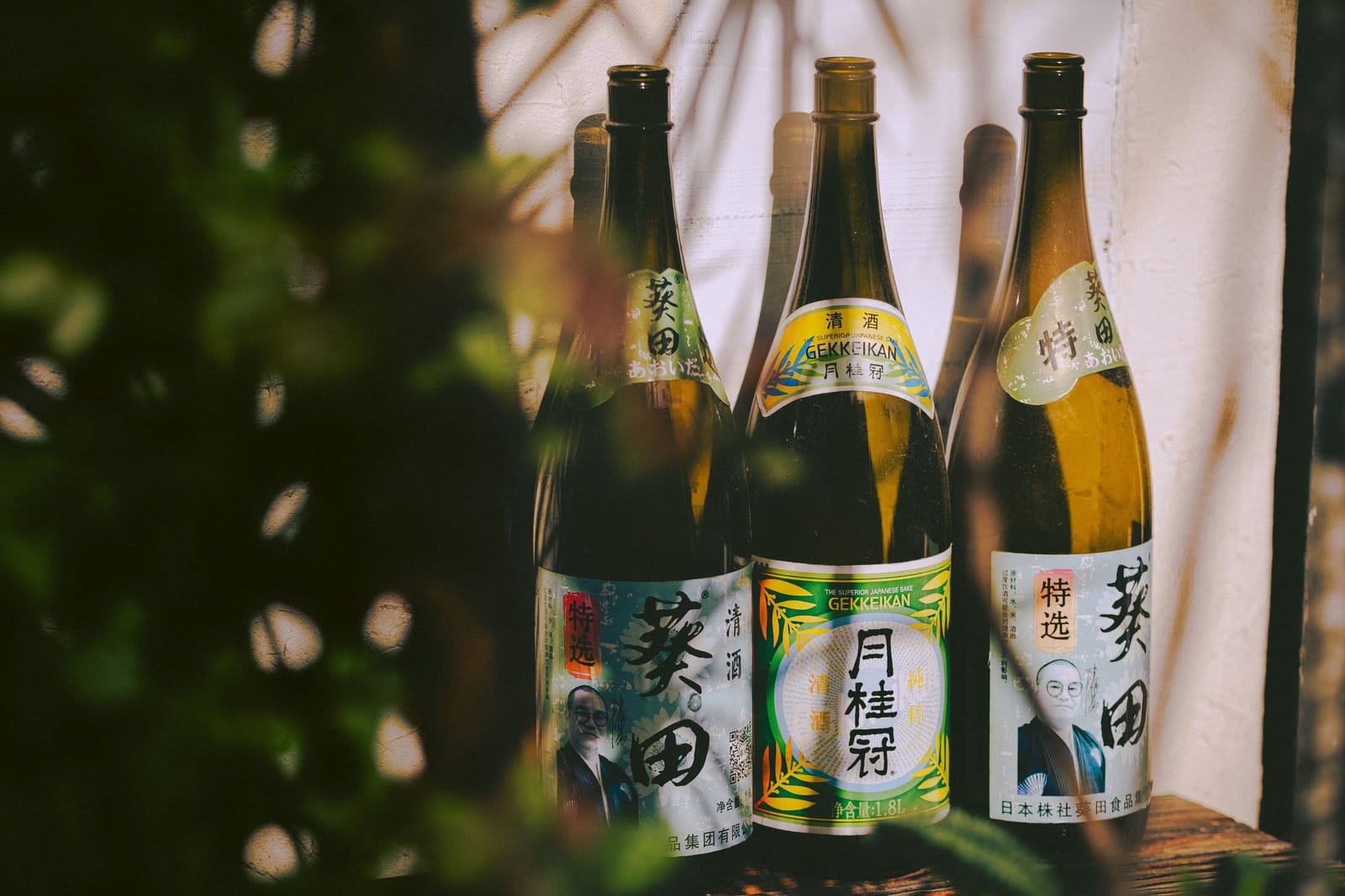 Three traditional Japanese sake bottles with paper labels in soft light