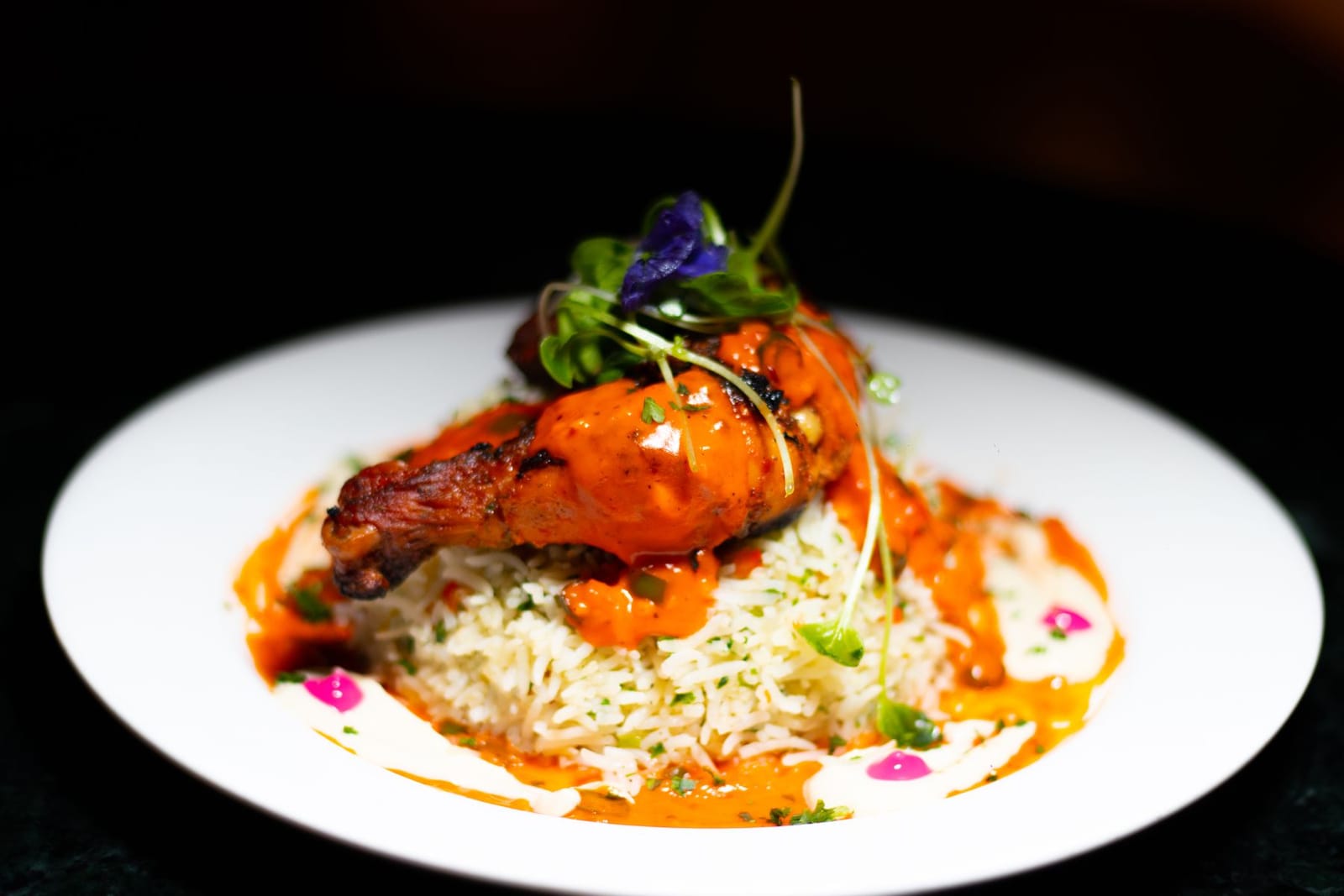 Fine-dining tandoori chicken plated with herbed rice and sauces