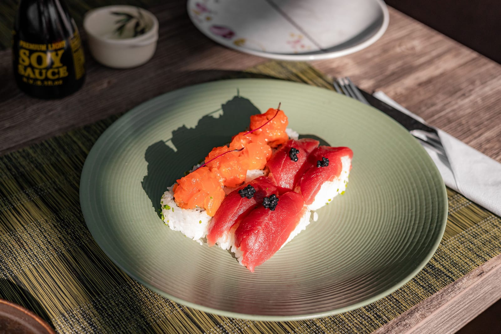 Close-up of nigiri sushi topped with caviar on a dark ceramic plate