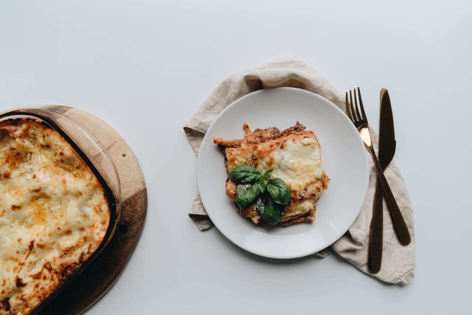 Lasaña vincisgrassi horneada con cobertura dorada de queso, en plato con albahaca