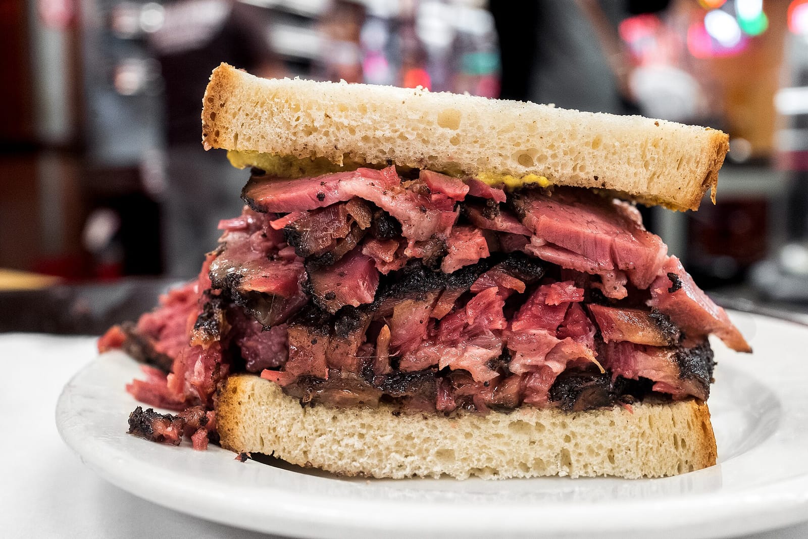Pastrami sandwich on rye with mustard on a white plate at Katz's Delicatessen