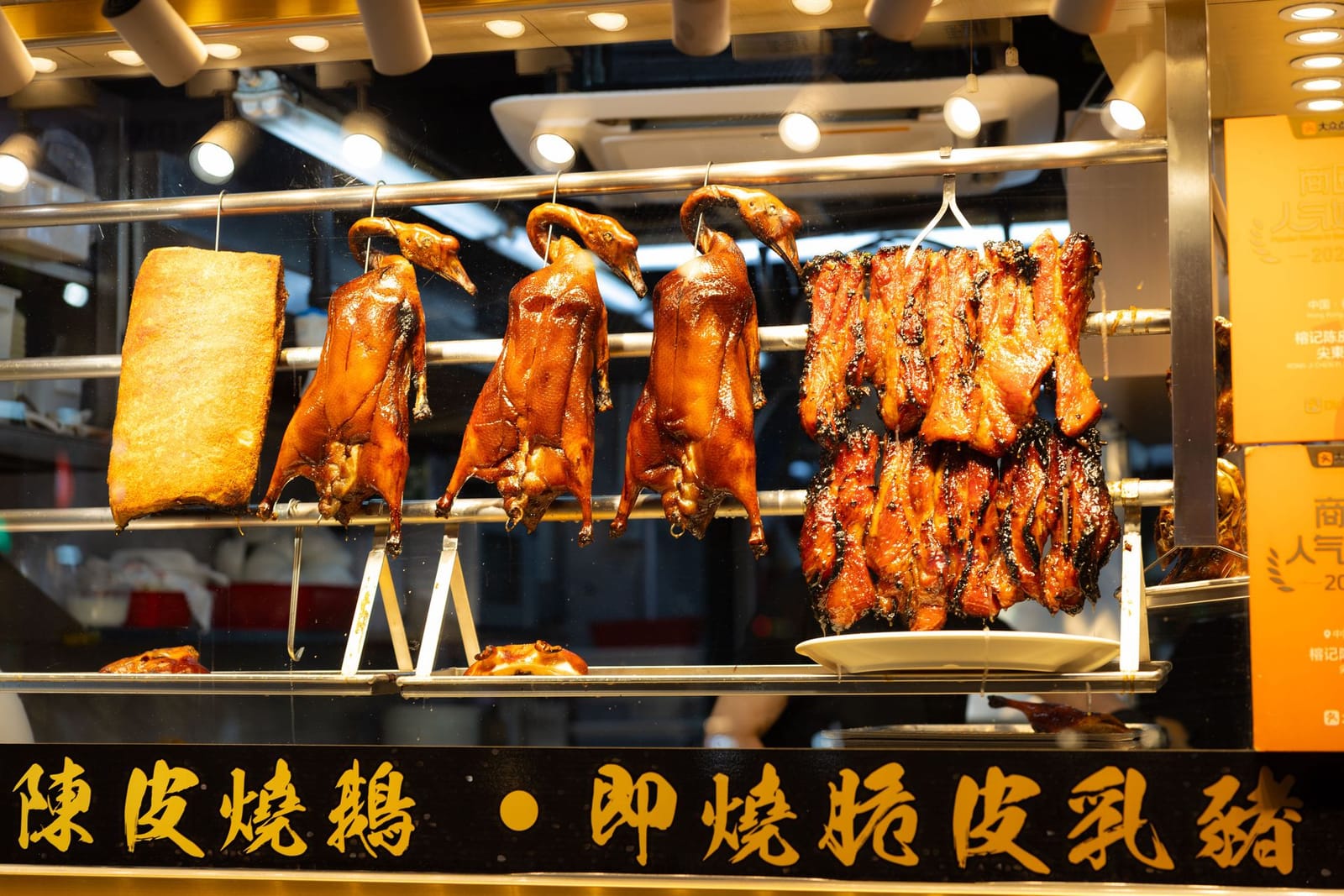 Glänzende gebratene Ente und Char Siu hängen in einem Schaufenster im Hongkong-Stil