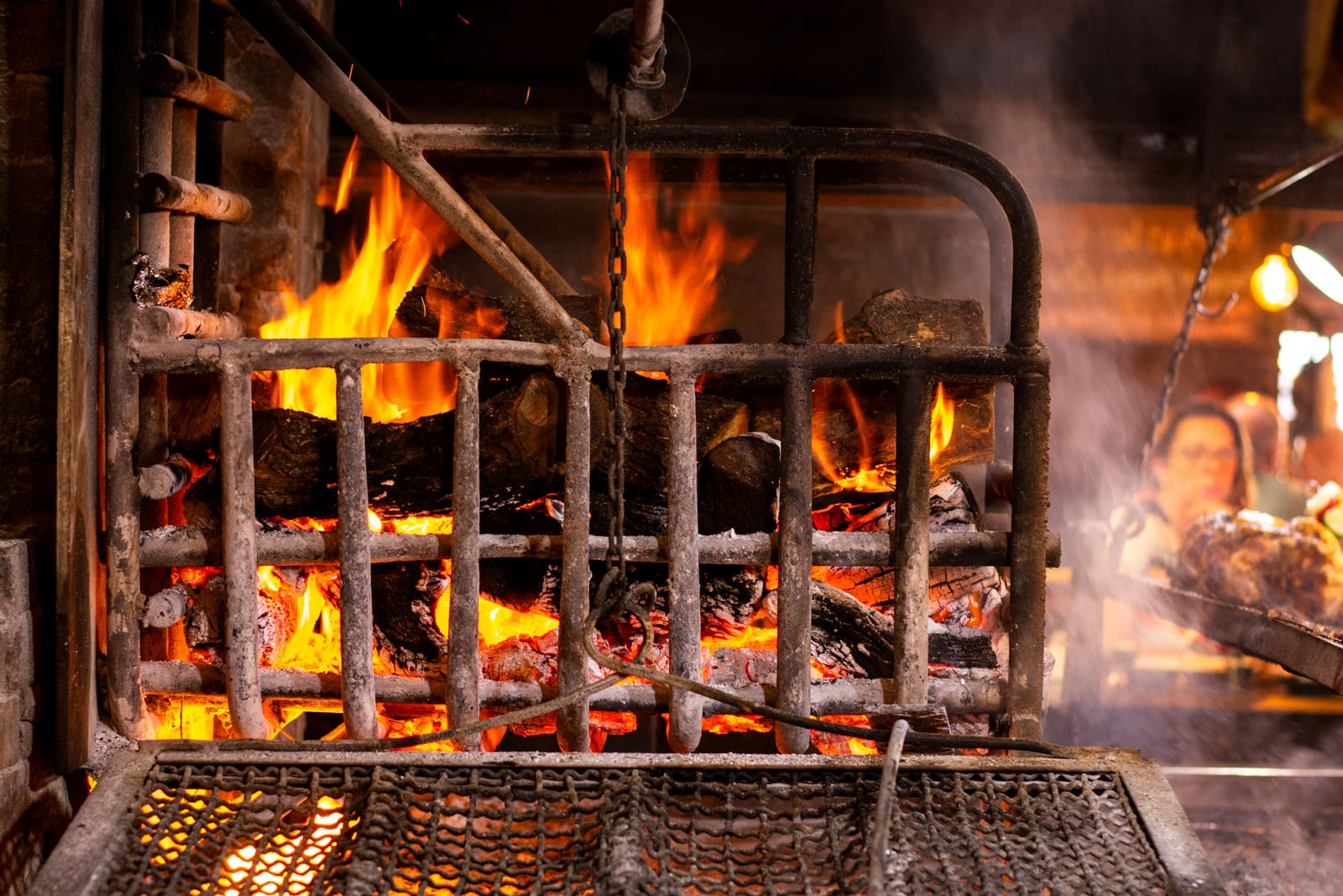 Flammen schlagen aus einem Holzkohlegrill in einer rustikalen Restaurantküche
