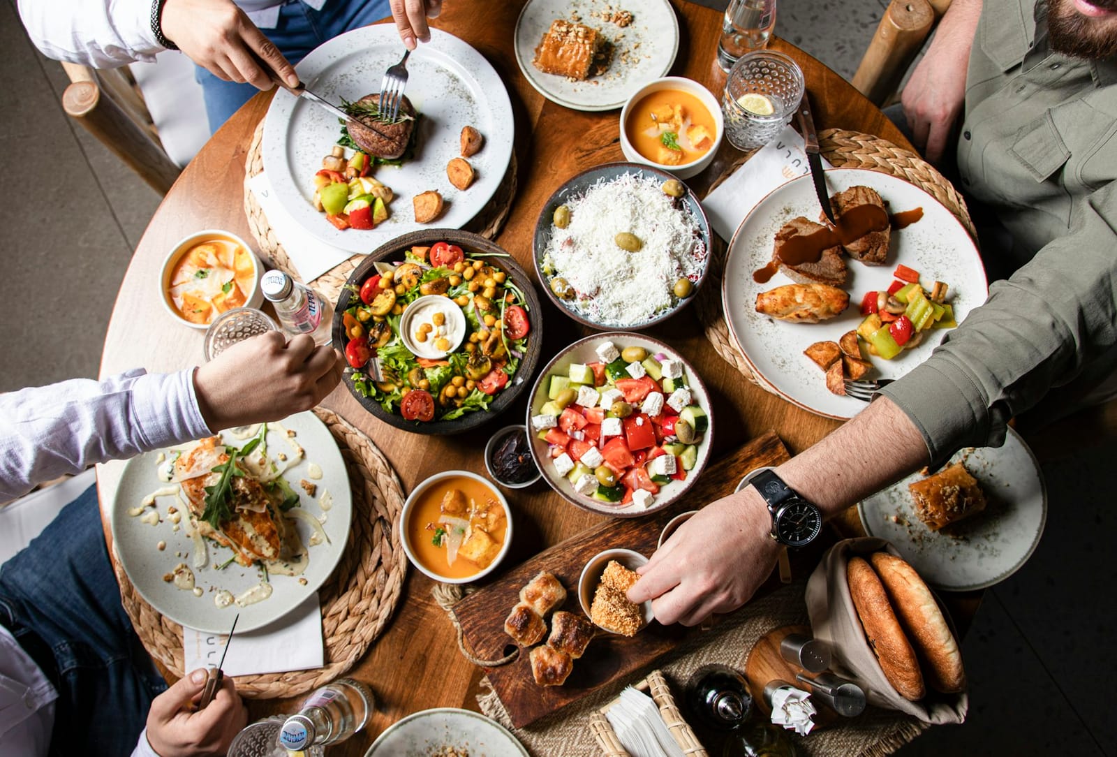 Overhead view of diners sharing several small plates at a round table