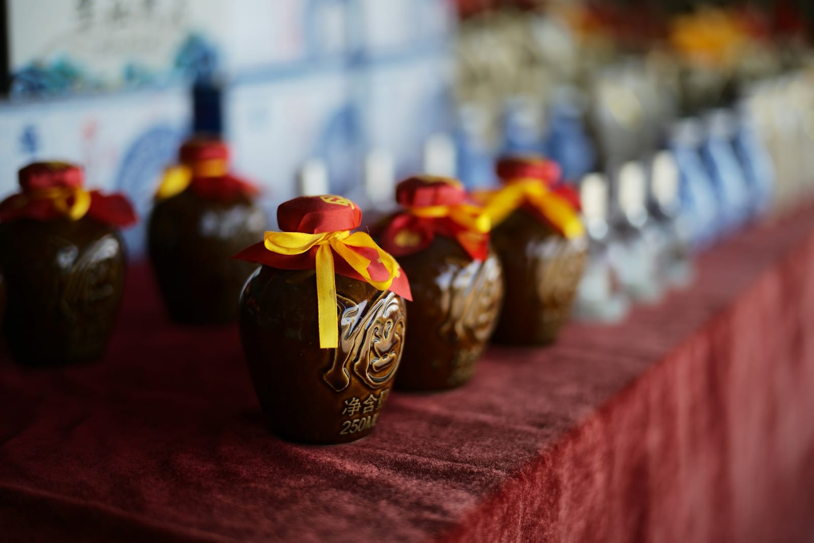Traditional ceramic baijiu jars tied with red and gold ribbons displayed in a row