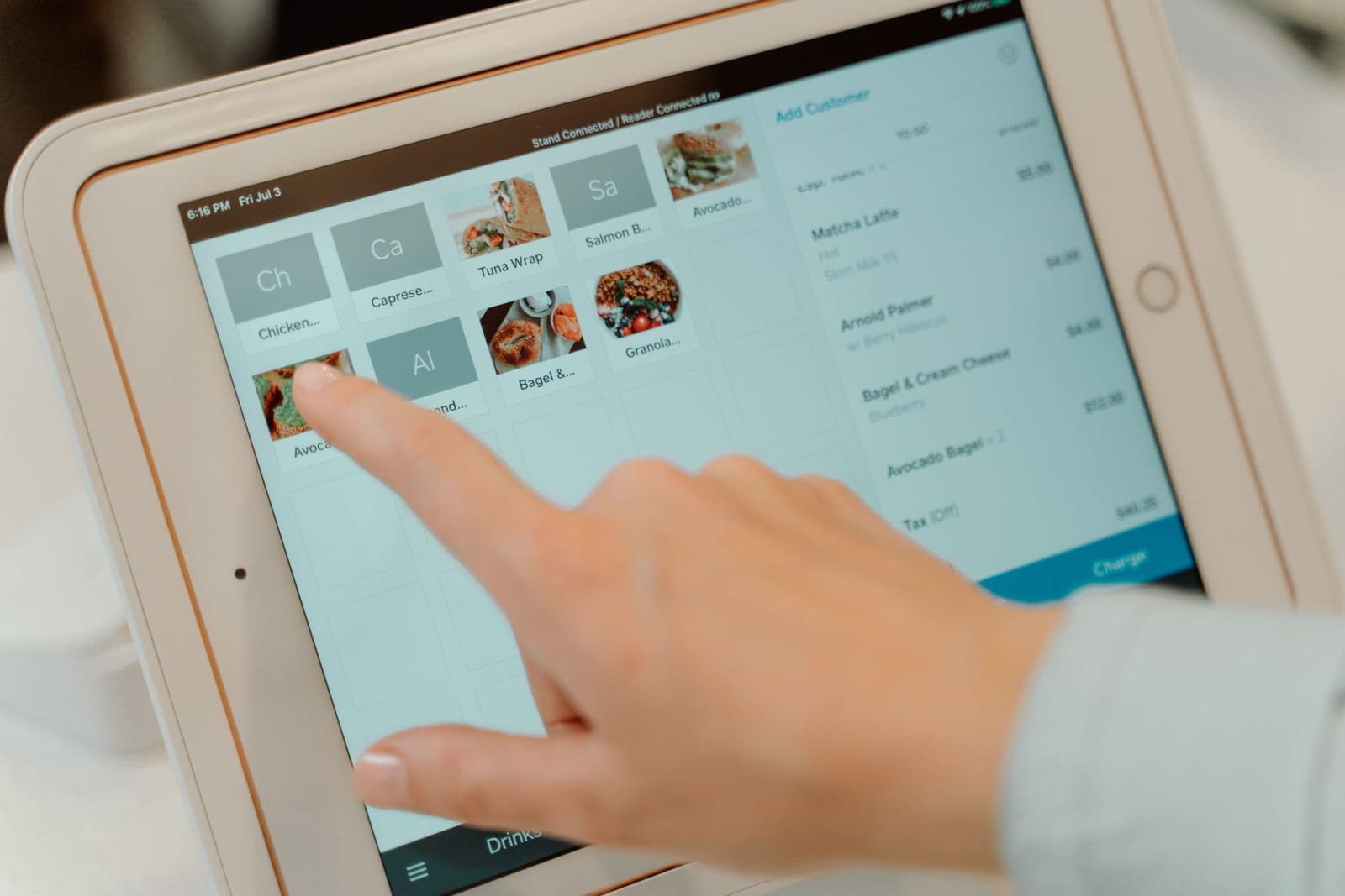 Een vinger kiest een gerecht op een bestelscherm op de toonbank van een café